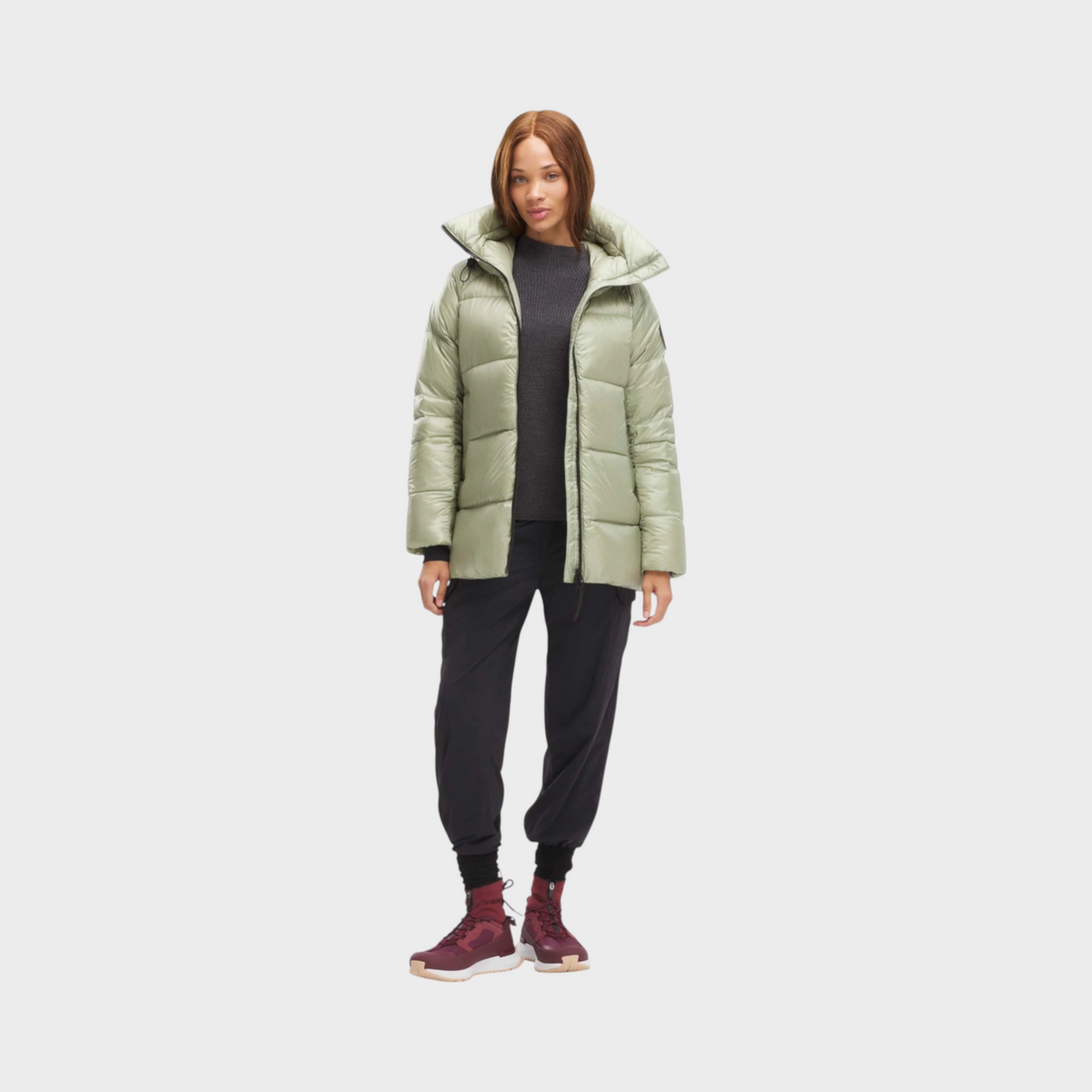 Model wearing a Supplied Fashion Canada Goose Cypress puffer jacket in cedar green with a high collar and down fill.