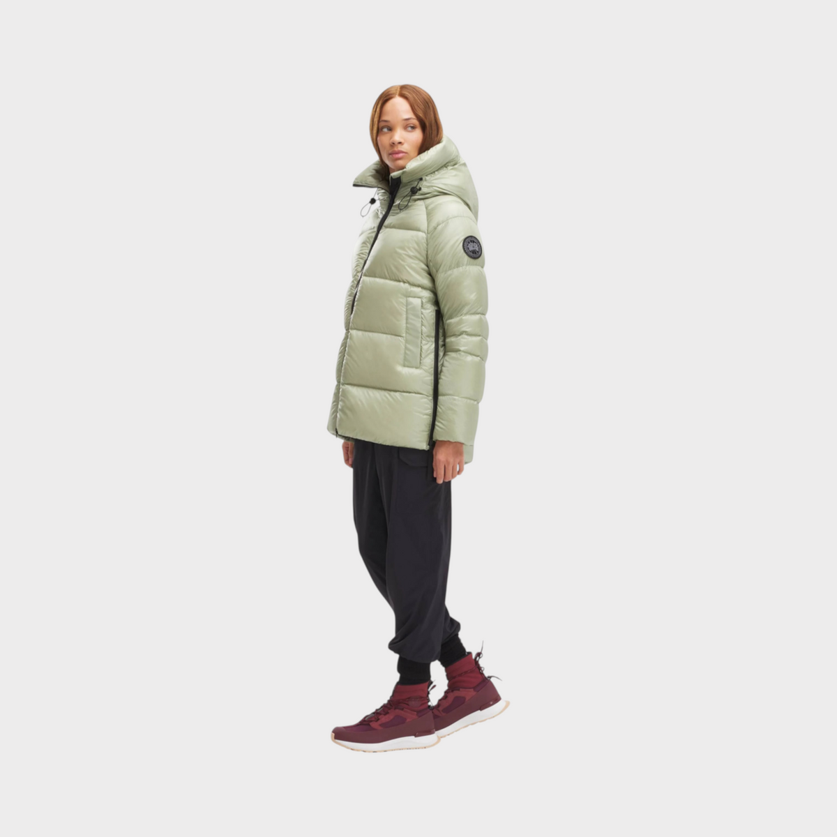Model wearing a Supplied Fashion Canada Goose Cypress Black Label puffer jacket in cedar green with a hood.