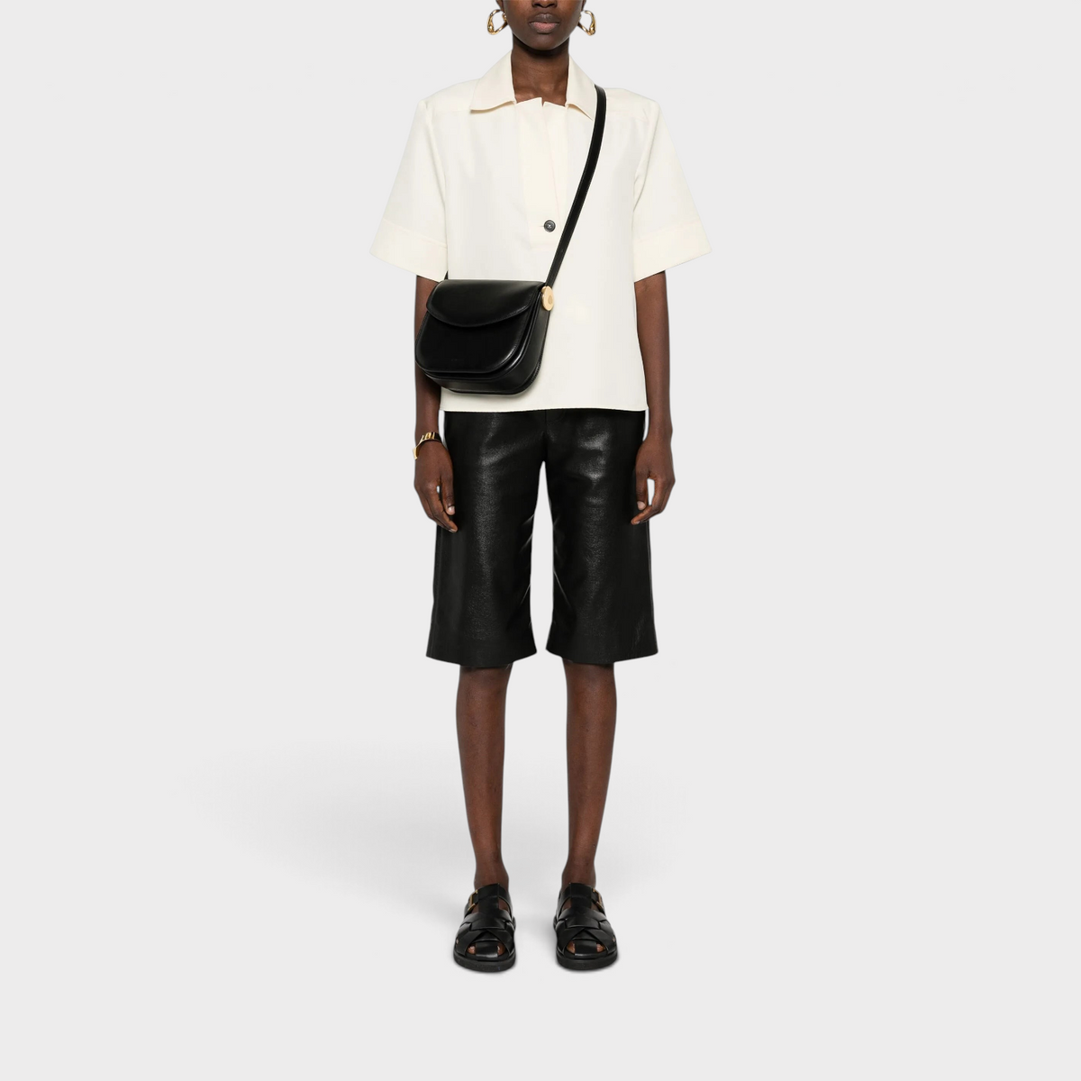 Supplied Fashion Medium Coin black leather crossbody bag with a structured silhouette worn by a model.