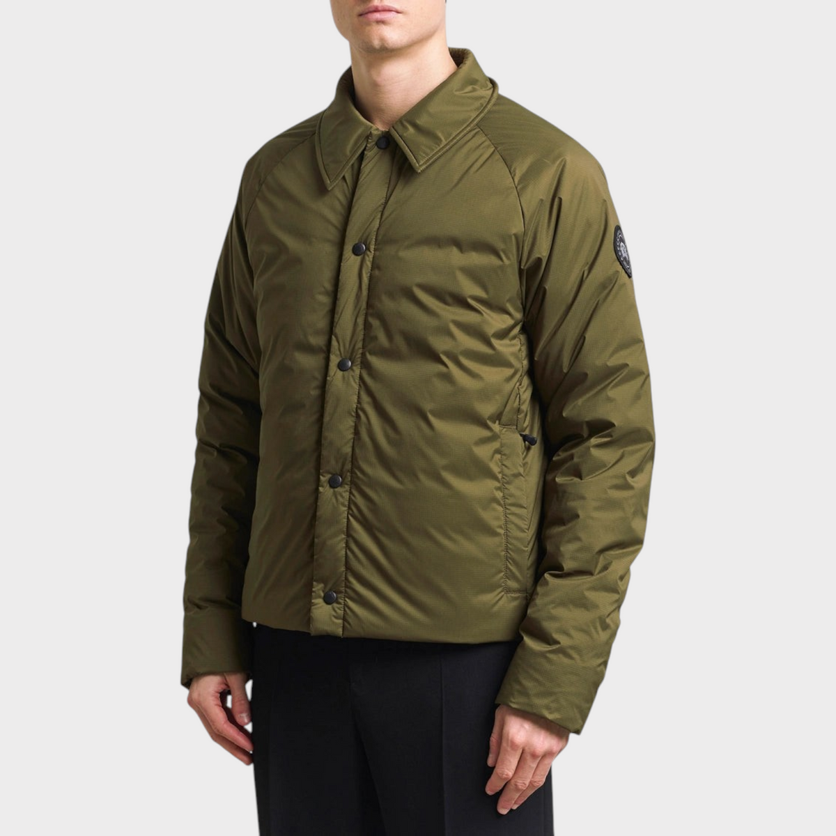 Supplied Fashion Lodge coach jacket in military green featuring a classic collar, snap buttons, and a sleeve patch.