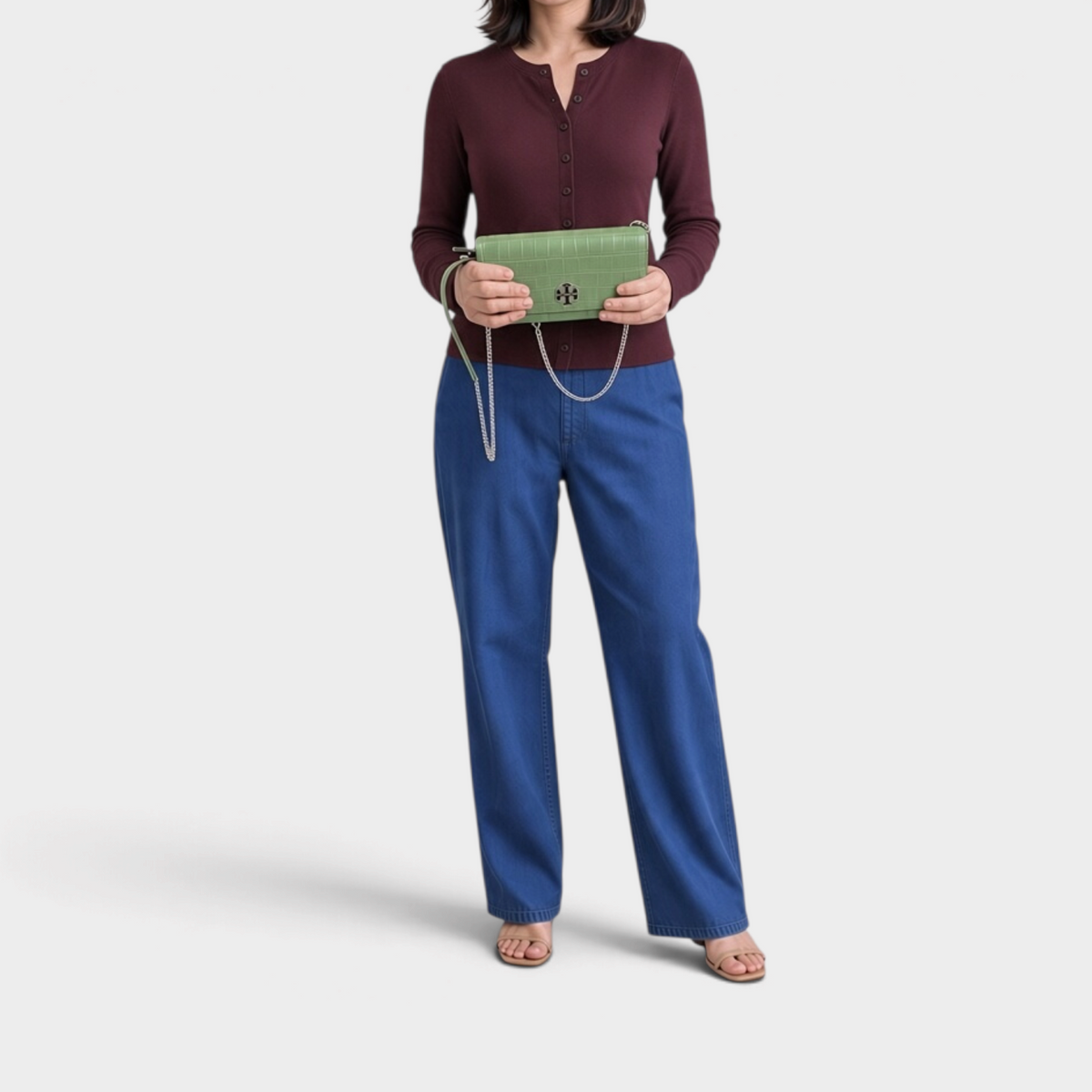 Supplied Fashion Willa palm green embossed chain wallet held by a woman in a burgundy cardigan and blue jeans