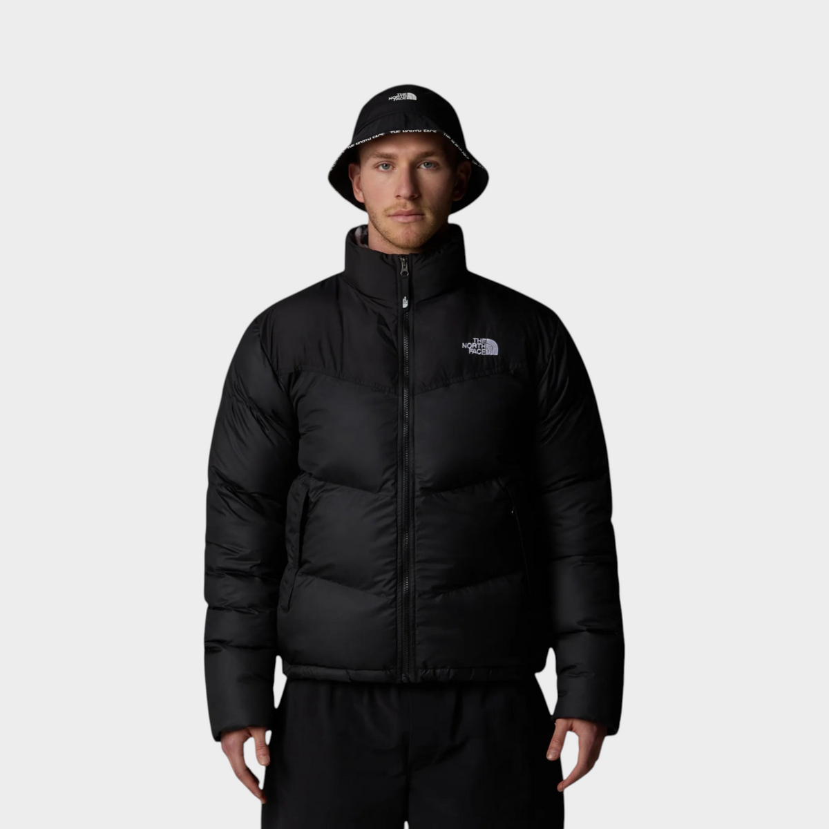 Supplied Fashion model wearing a black The North Face Saikuru puffer jacket and matching bucket hat