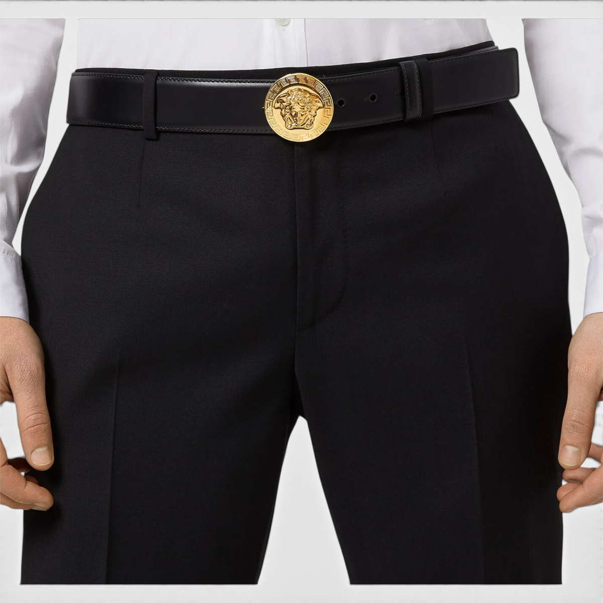 Supplied Fashion black leather belt featuring a round gold Medusa head buckle worn with tailored trousers and shirt