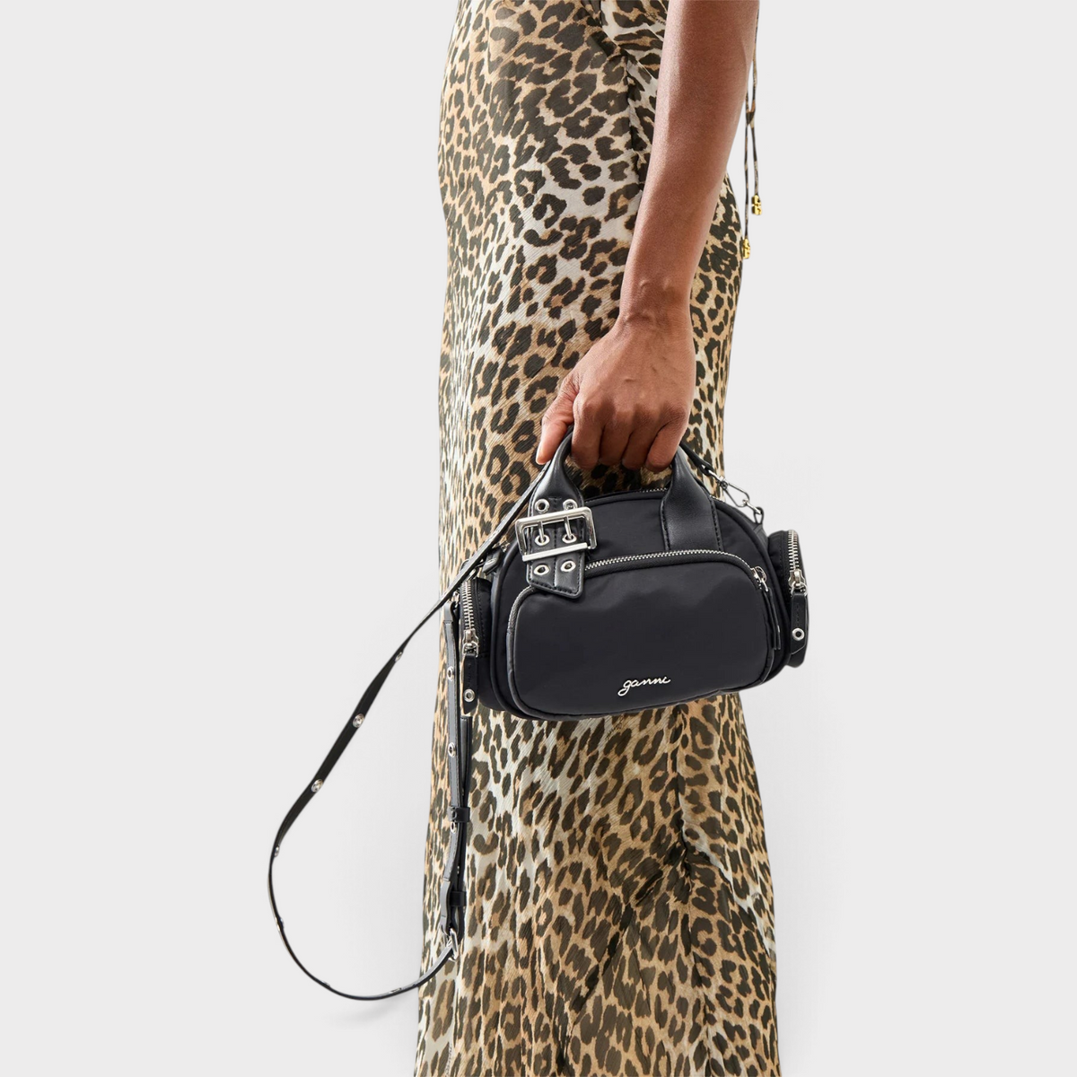 Supplied Fashion Bucky Polochon small black satchel with silver buckle detail held by a woman in a leopard print dress