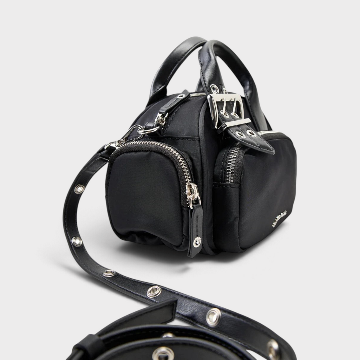 Supplied Fashion Bucky Polochon small black satchel with silver hardware, top handle, and adjustable grommet strap.