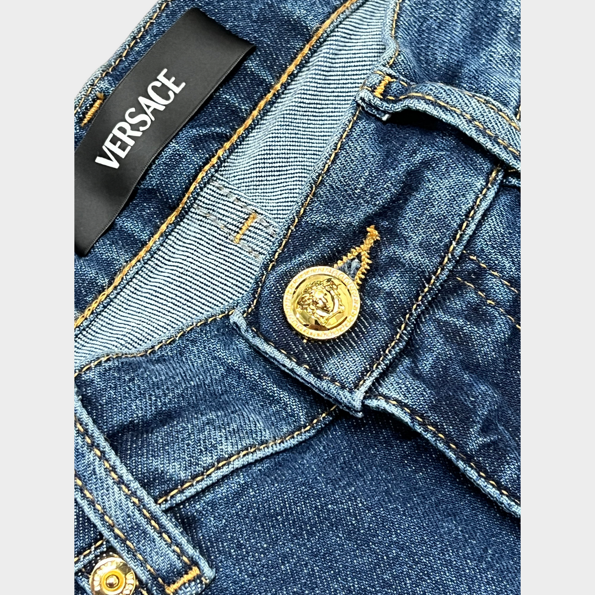 Supplied Fashion Versace blue denim jeans featuring a gold Medusa head button and branded black waist label