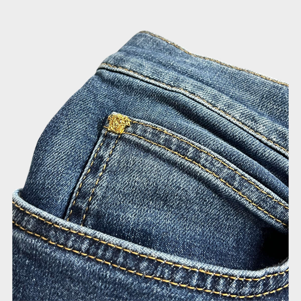 Supplied Fashion blue denim jeans featuring a gold Medusa head embellishment on the coin pocket with contrast stitching