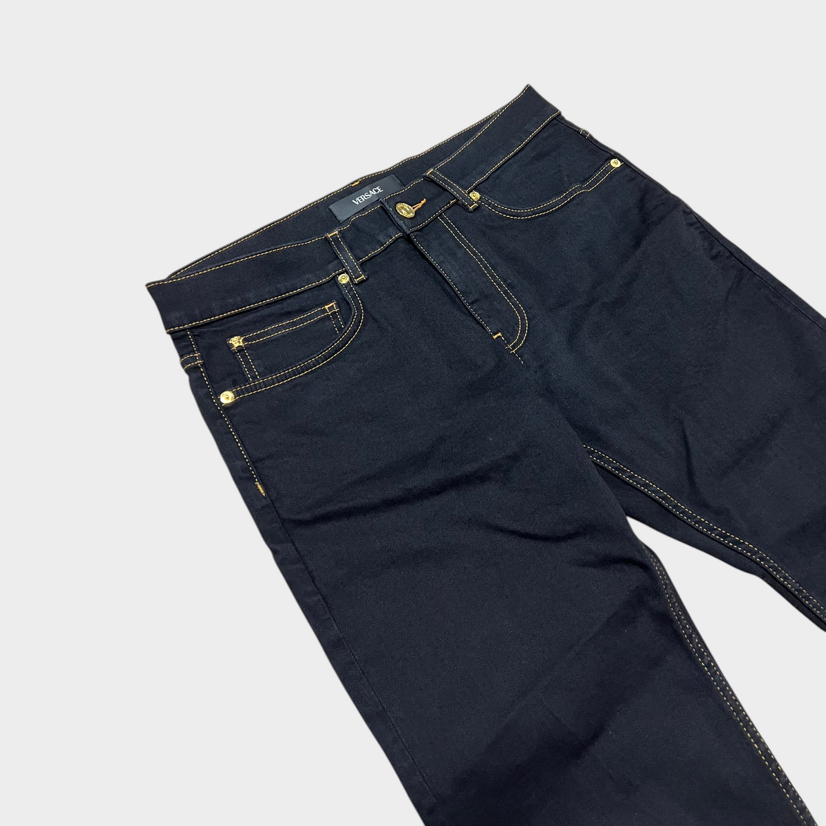 Supplied Fashion black stretch denim jeans with gold-tone Medusa head button detailing and contrast stitching.