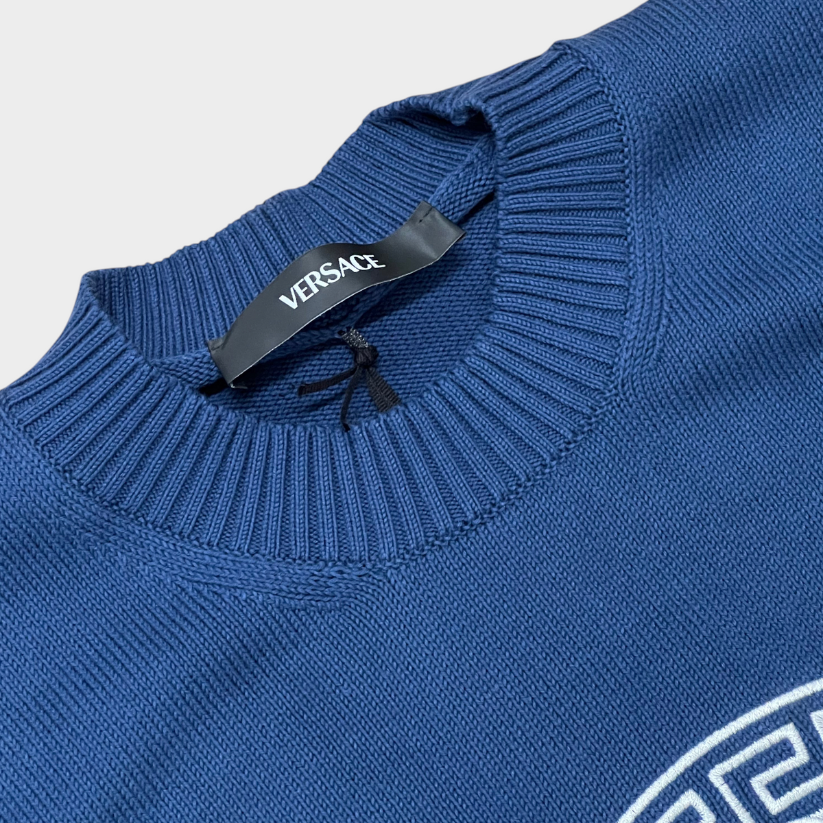 Supplied Fashion blue knit sweater featuring a ribbed crew neck and white Medusa head embroidery detail.
