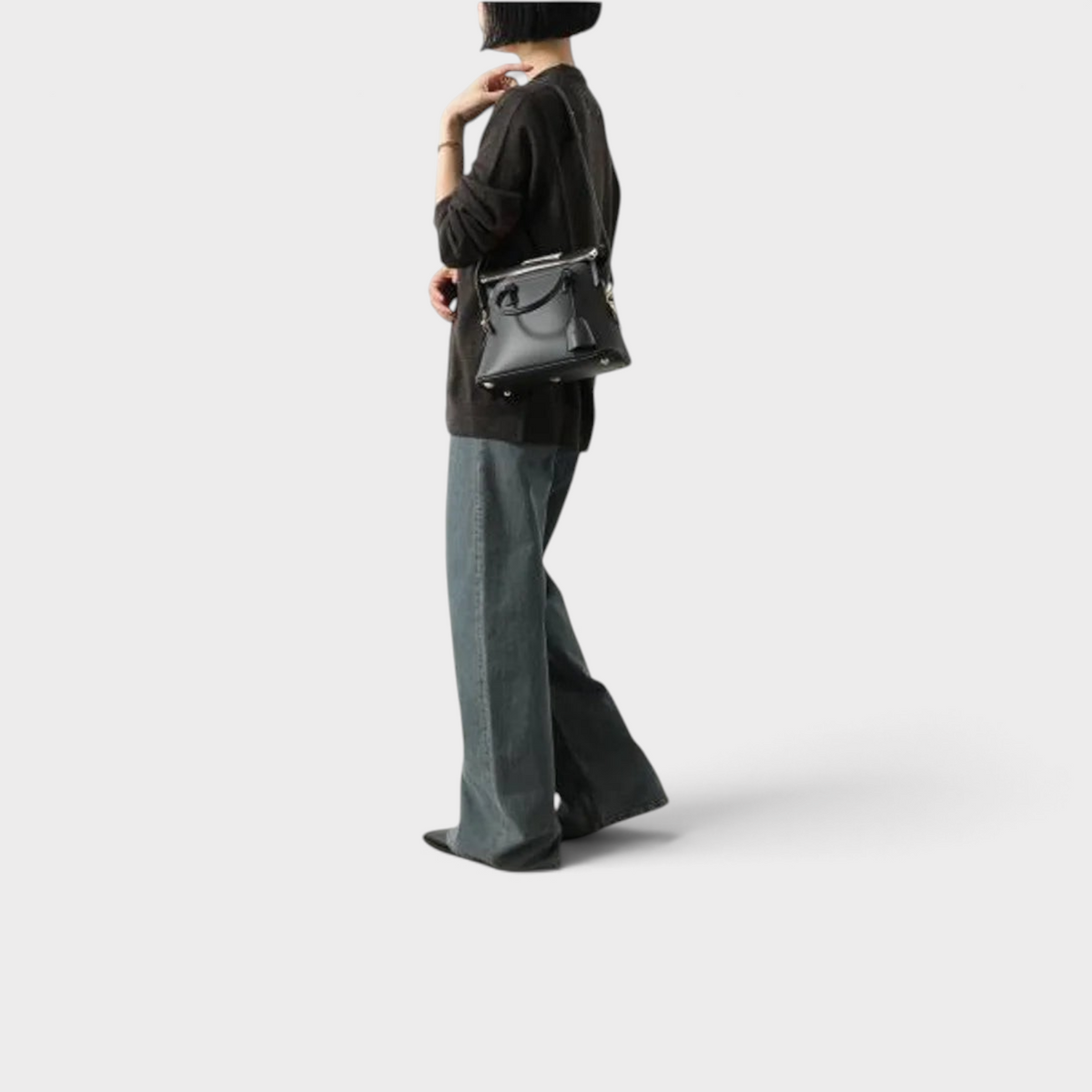 Supplied Fashion Maison Margiela 5AC mini black leather tote bag worn over the shoulder by a woman in casual attire.
