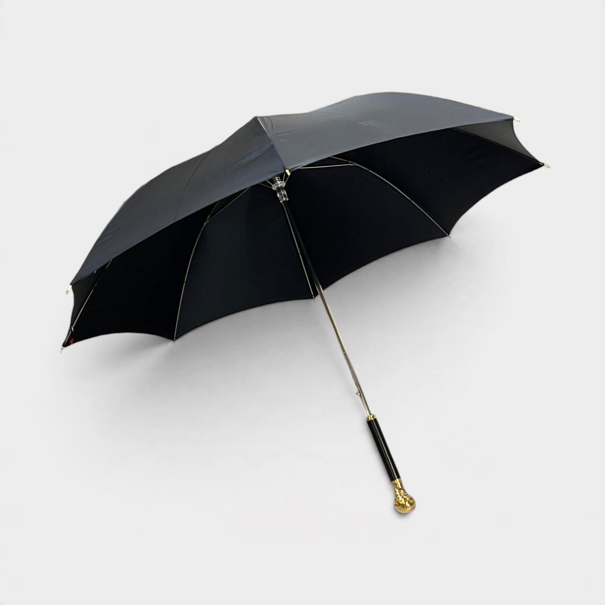 Supplied Fashion Alexander McQueen black umbrella with a gold skull handle and wood detailing against a white background