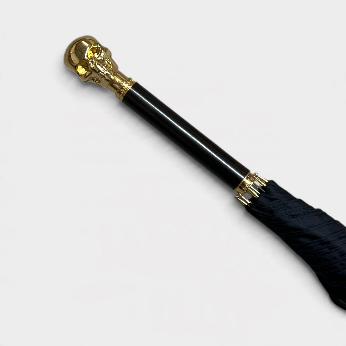 Supplied Fashion Alexander McQueen umbrella featuring a gold skull handle with wood detailing and black fabric canopy.