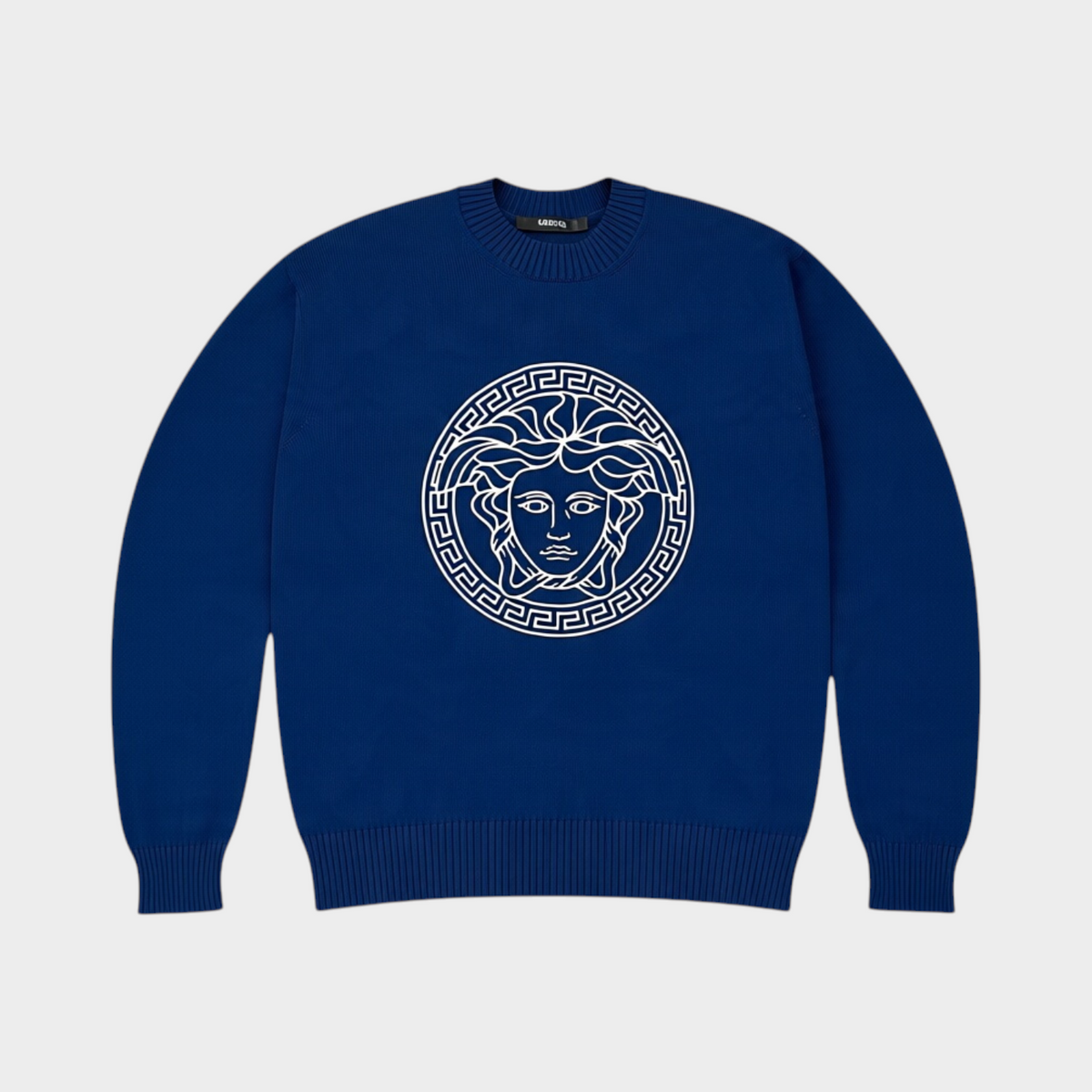 Supplied Fashion blue knit sweater featuring a white embroidered Medusa head motif and classic crew neck design.