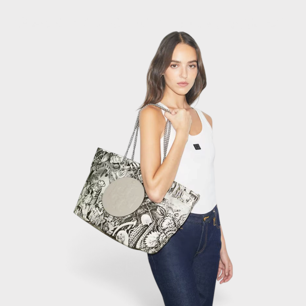 Supplied Fashion Ella grey alien printed tote bag with chain straps carried by a woman in a white tank top