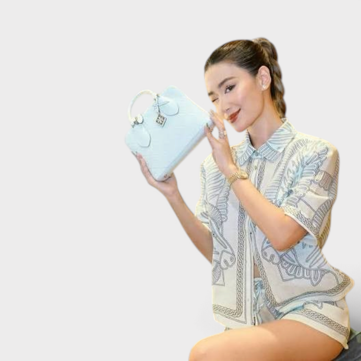 Supplied Fashion ice blue leather mini swing bag with monogram T logo held by a woman in a matching patterned set