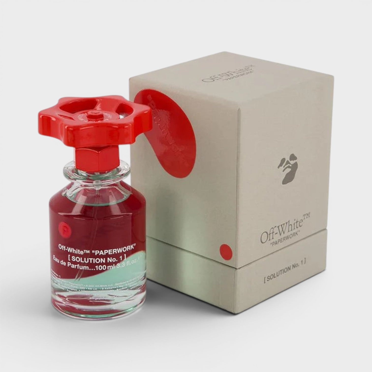 Red perfume bottle with a matching cap next to its packaging box on a white background