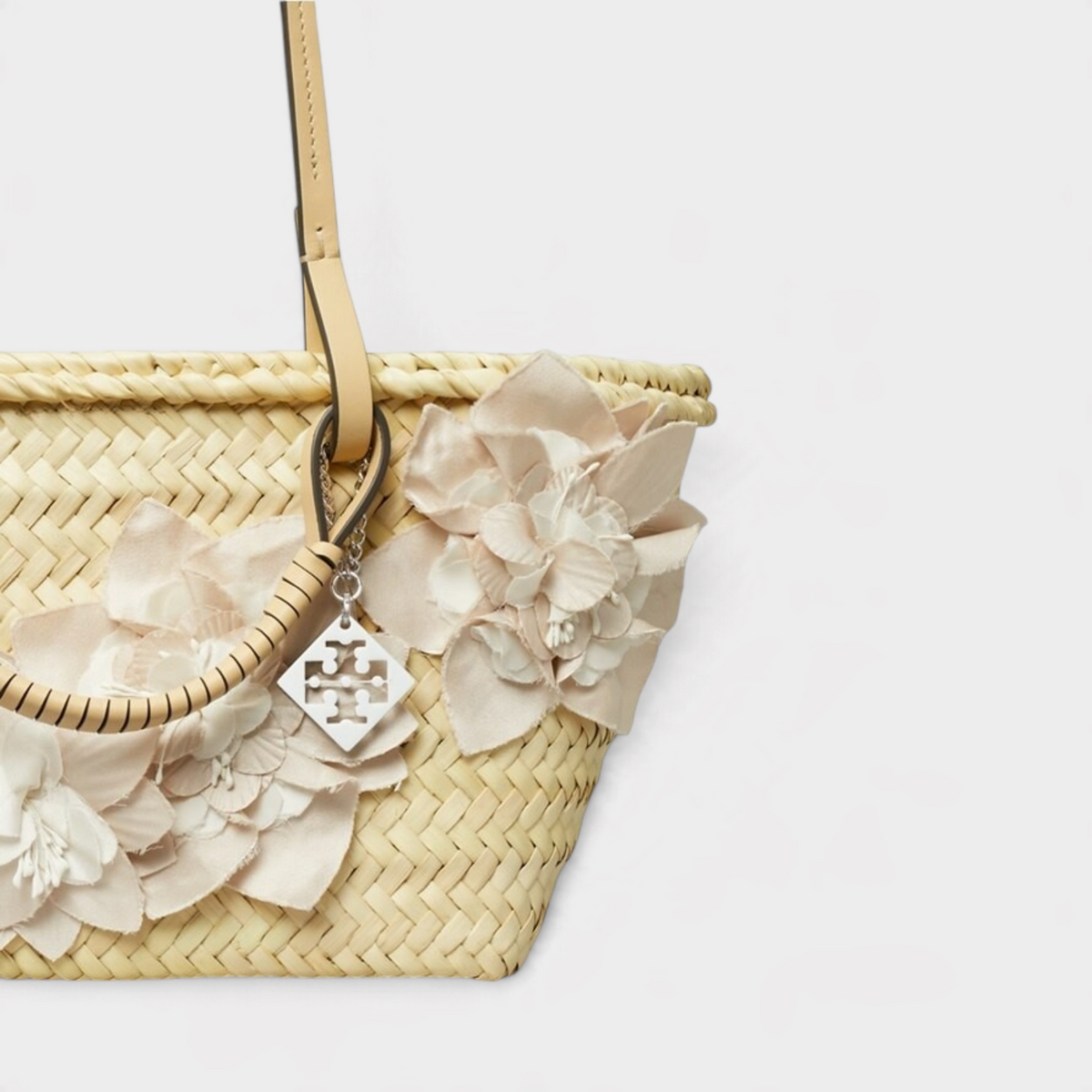 Supplied Fashion small beige woven straw tote bag featuring delicate fabric floral embellishments and a metal charm.