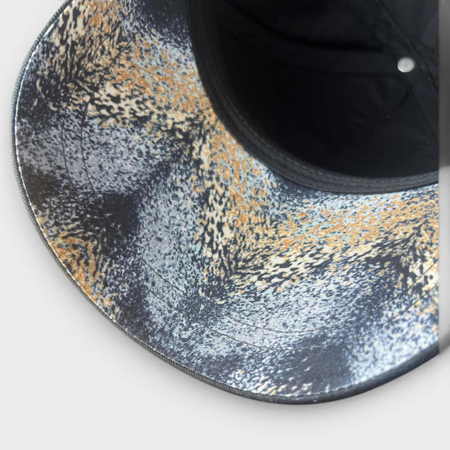 Supplied Fashion black cap featuring a textured abstract grey and gold pattern on the brim