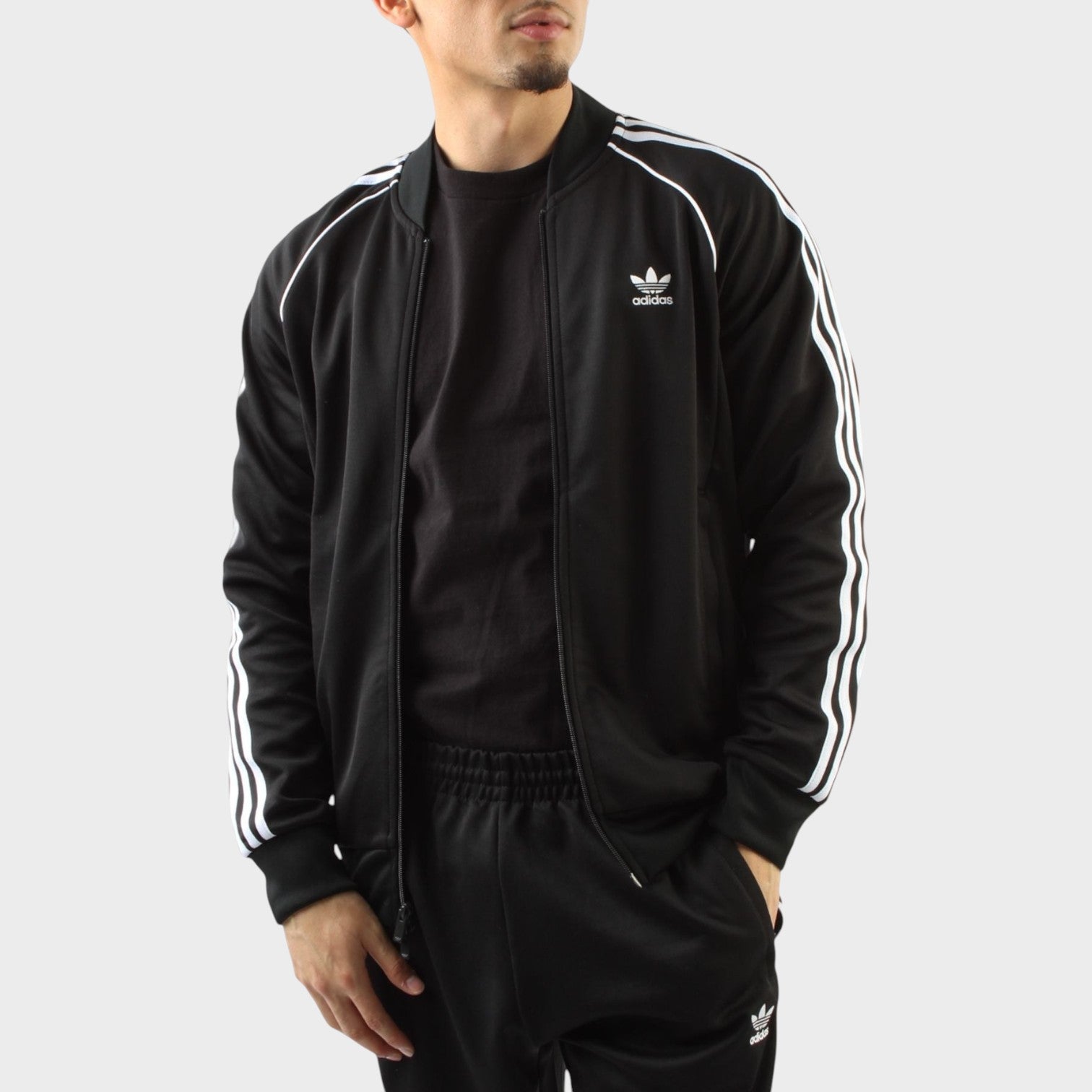 Supplied Fashion adidas Adicolor Classics black track top with white three-stripe detailing and ribbed cuffs.