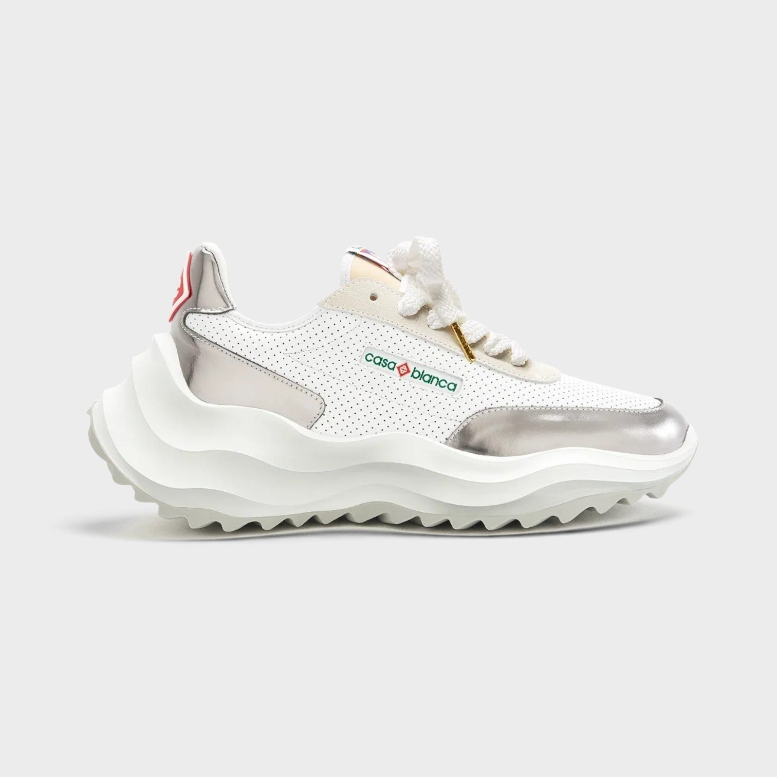 Supplied Fashion Atlantis sneaker in white perforated leather with metallic chrome accents and a chunky wavy sole.
