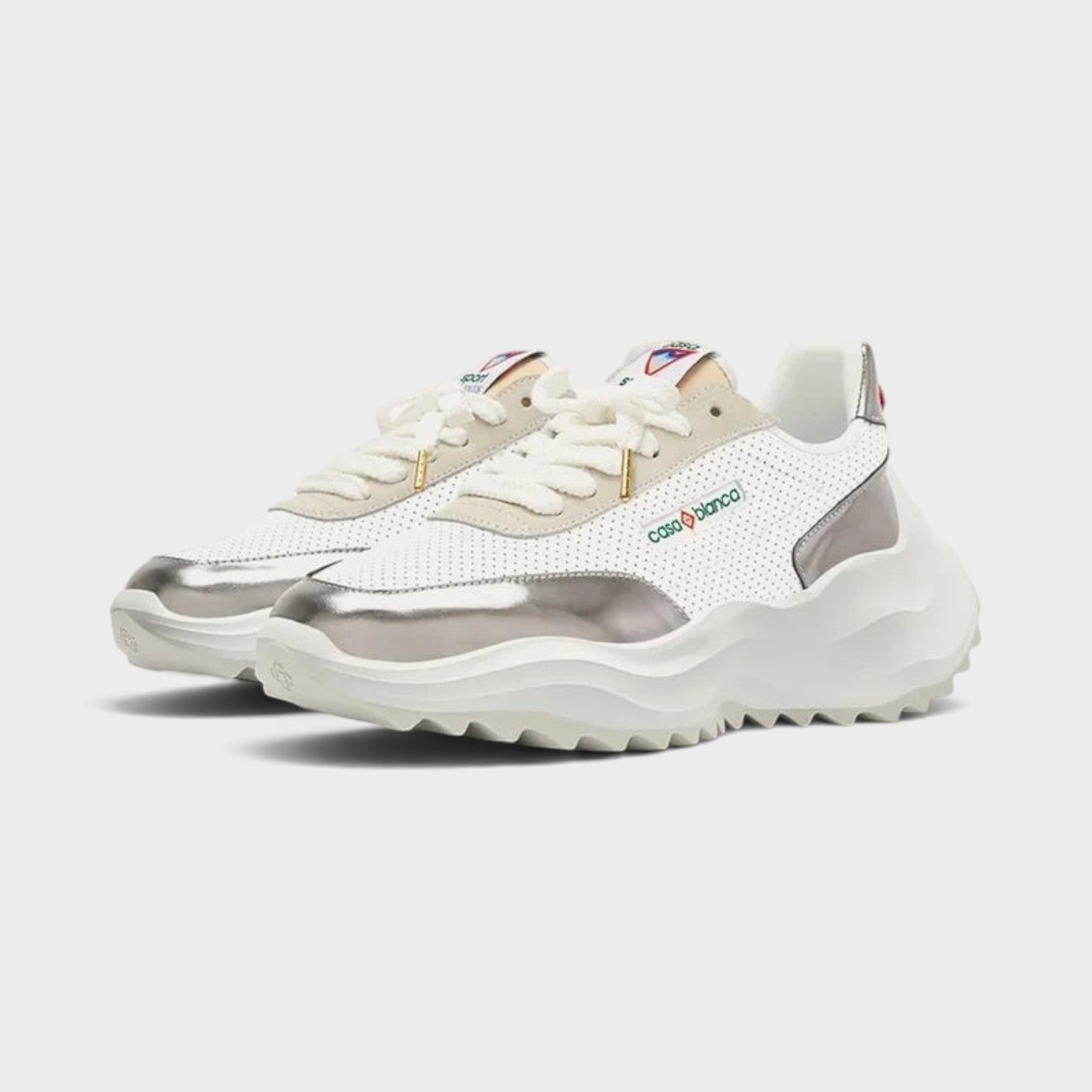 Supplied Fashion Atlantis sneaker in white with chrome metallic accents, featuring a chunky sole and perforated upper.