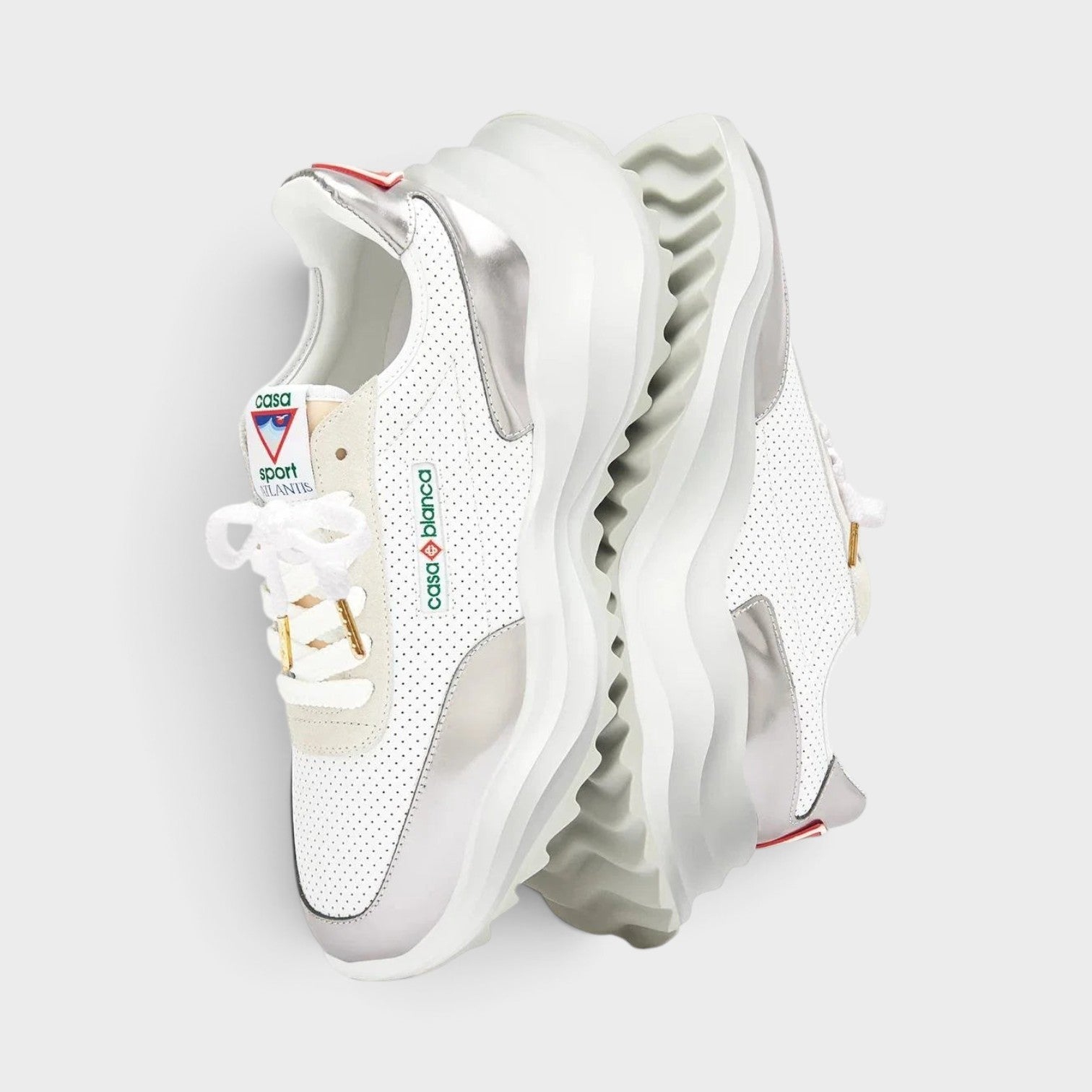 Supplied Fashion Atlantis sneaker in white with chrome accents, featuring a perforated leather upper and chunky sole.