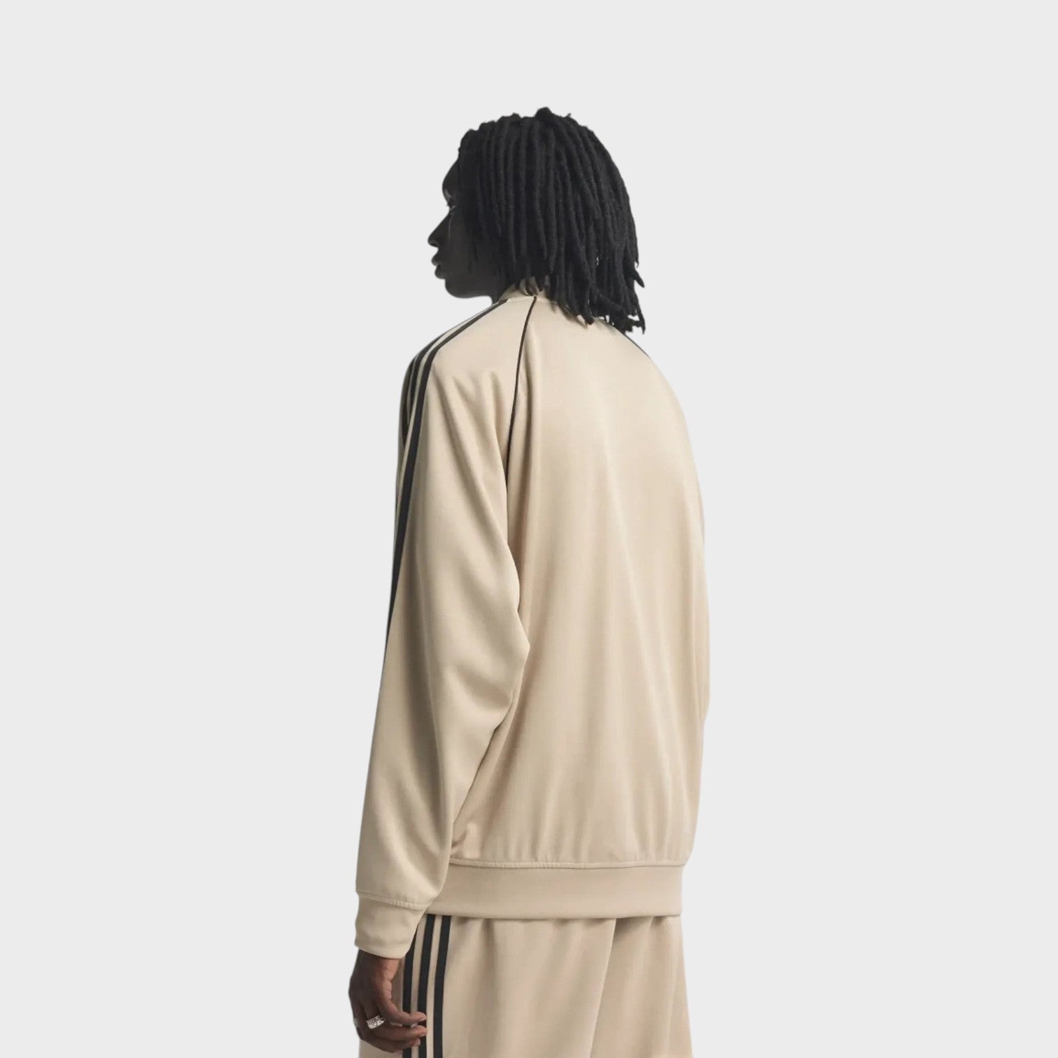 Supplied Fashion beige and black loose track top with iconic three-stripe detailing worn by a model from behind