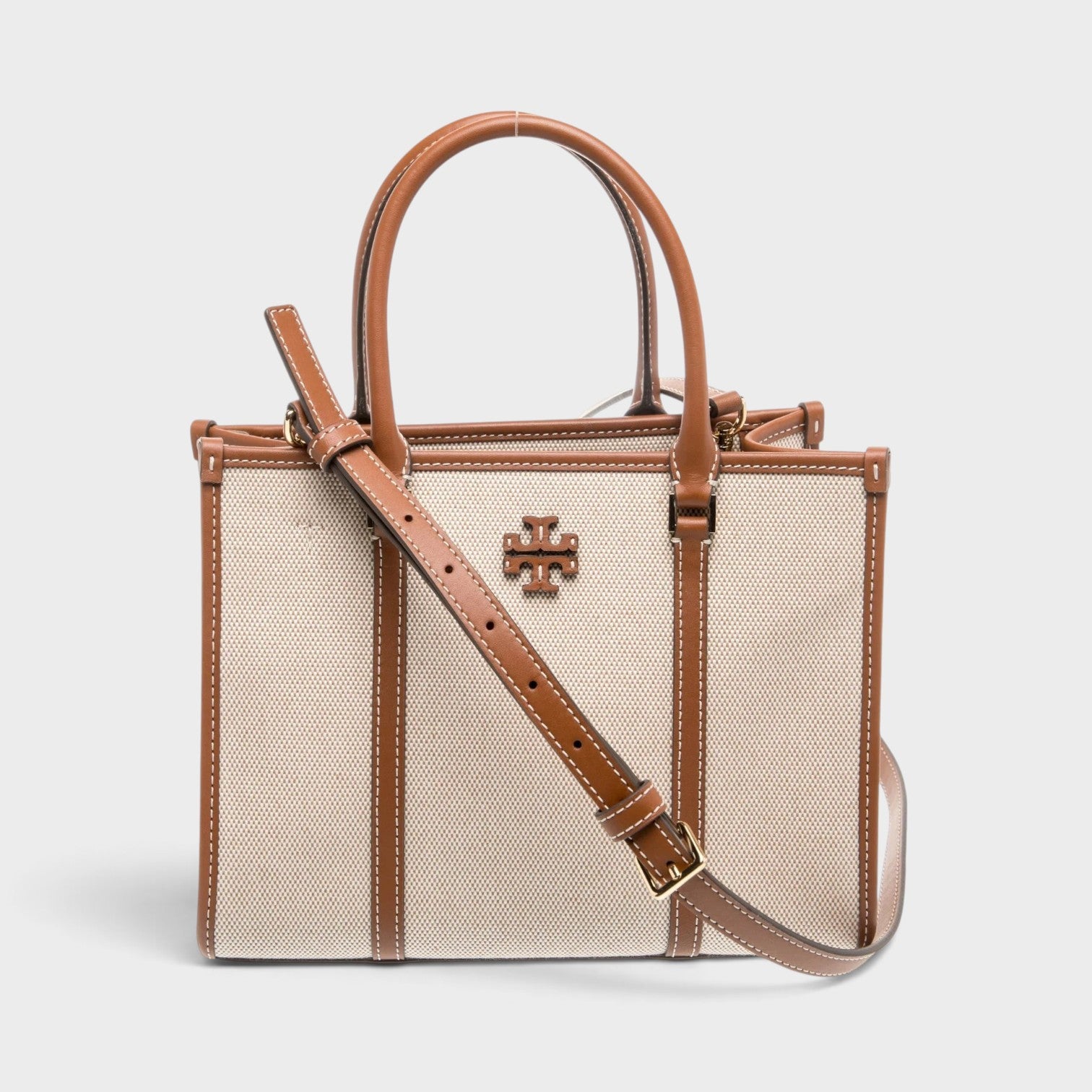 Supplied Fashion beige canvas top-handle bag with brown leather trim, gold logo hardware, and adjustable strap.