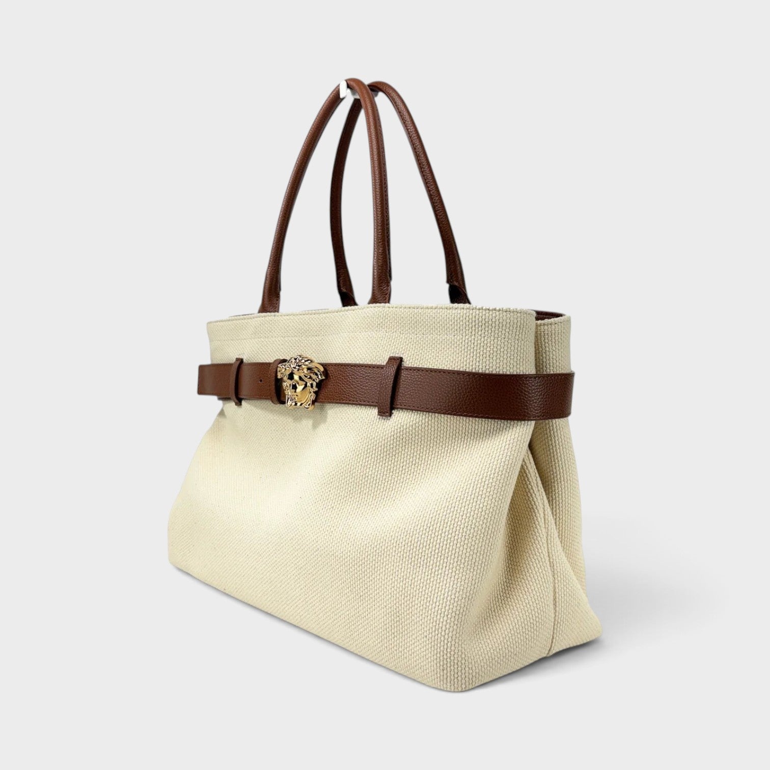 Supplied Fashion beige canvas tote bag with brown leather handles, belt detail, and gold Medusa head emblem.