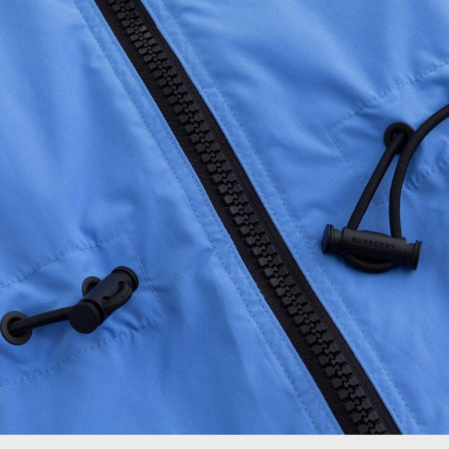 Supplied Fashion Birley long blue jacket featuring a black front zipper and adjustable drawstring toggles.