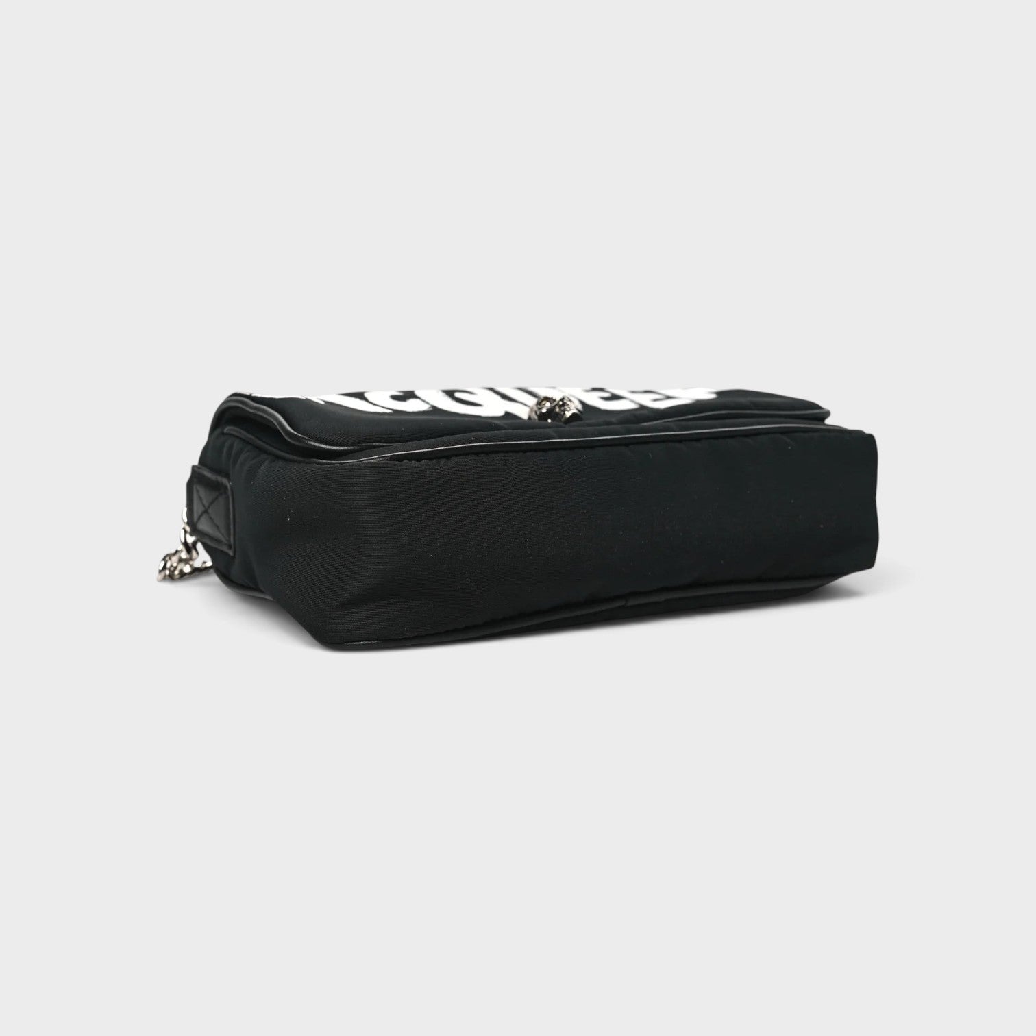 Supplied Fashion black nylon crossbody bag with white graffiti skull logo, side view showing compact design.