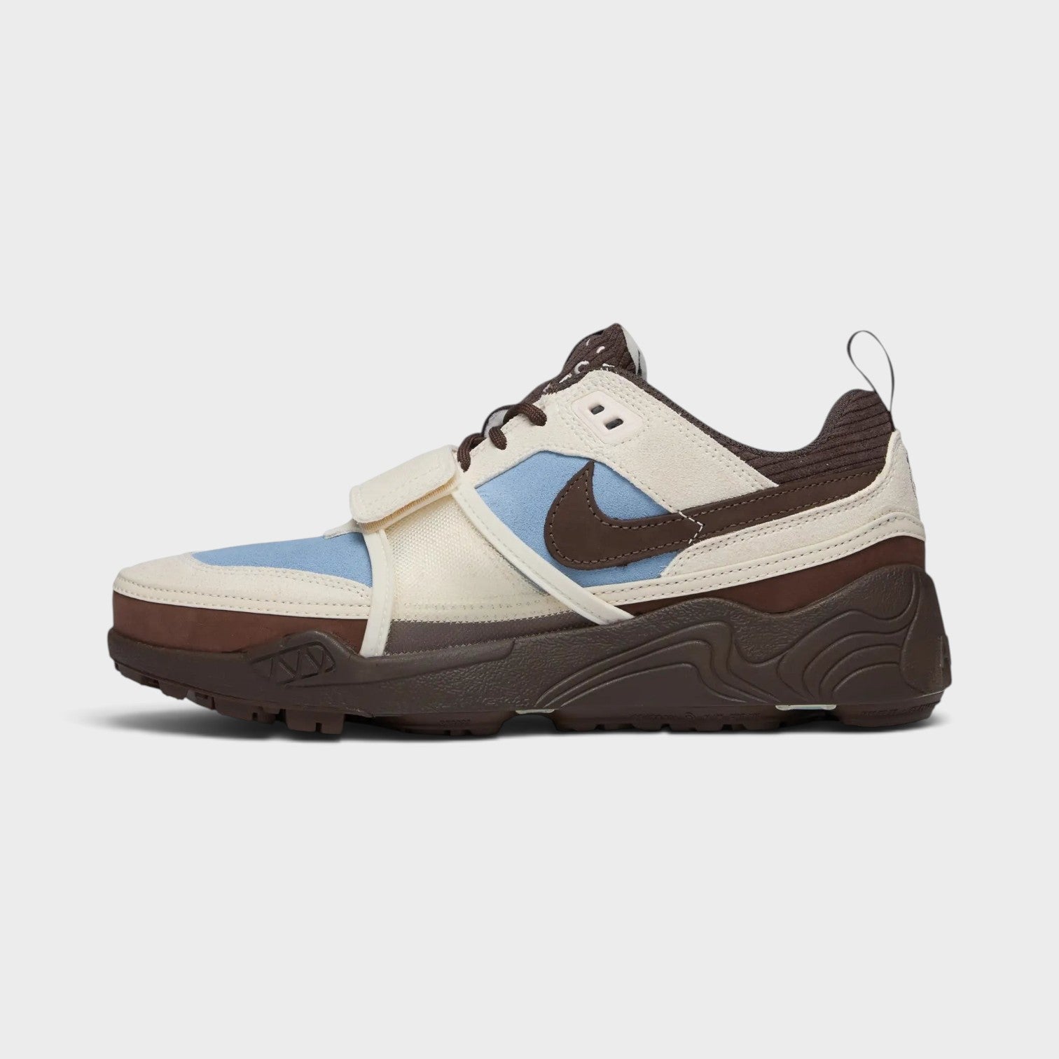 Supplied Fashion Cactus Jack Zoom Field Jaxx sneaker in pale ivory, blue, and brown with a side strap and swoosh
