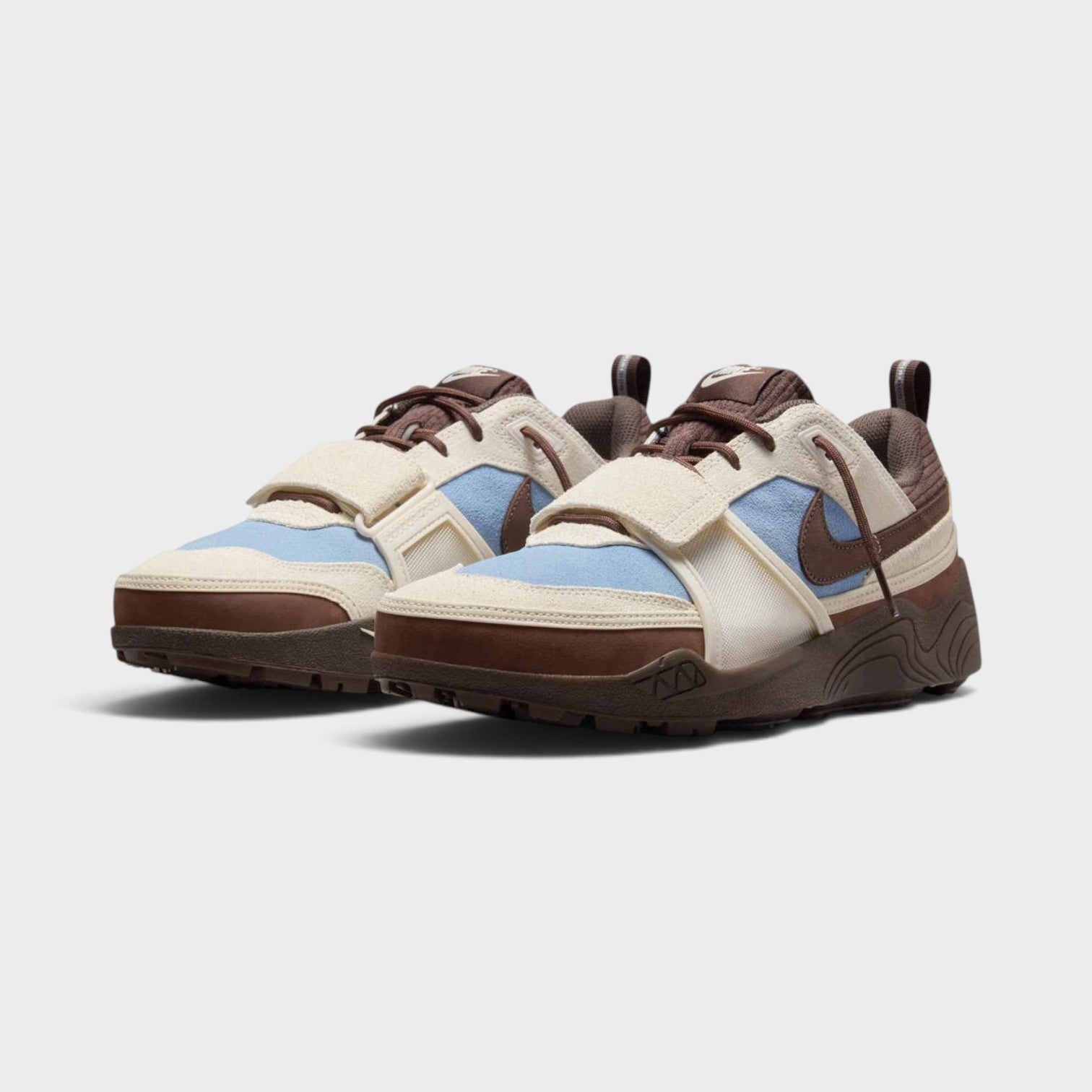 Supplied Fashion Cactus Jack Zoom Field Jaxx sneakers in pale ivory, light blue, and brown with a midfoot strap.