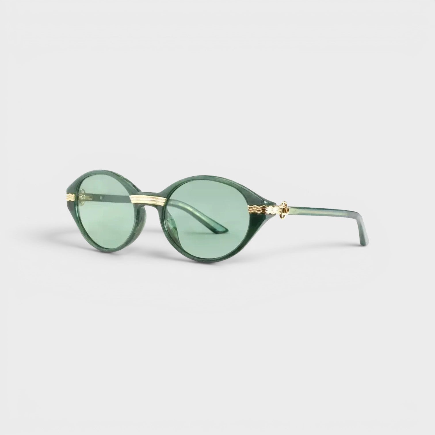 Supplied Fashion Cannes sunglasses featuring round green lenses and elegant gold-tone metal accents on a dark frame.