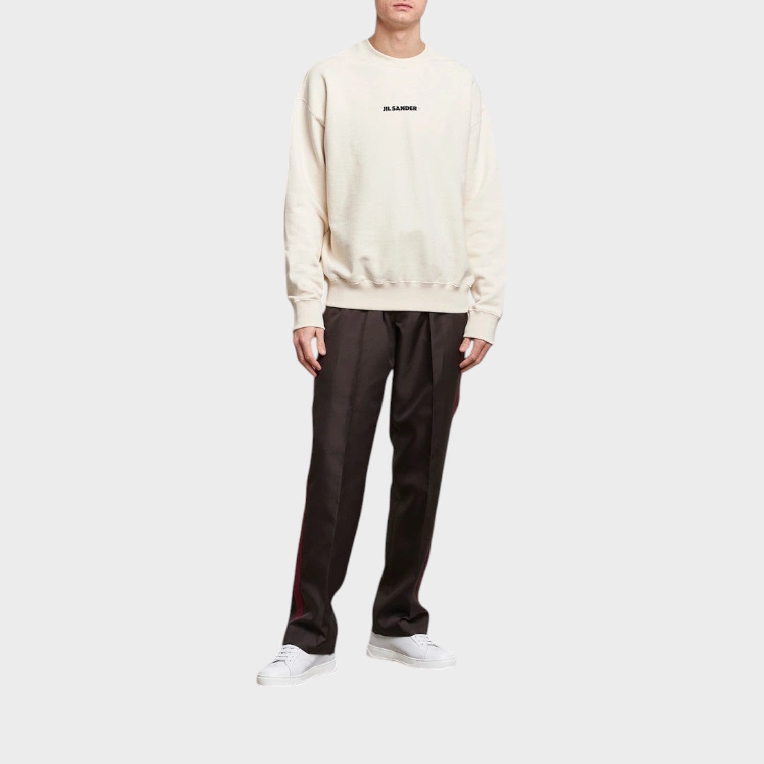 Supplied Fashion Jil Sander cream terry logo sweatshirt worn by a model with dark trousers and white sneakers.