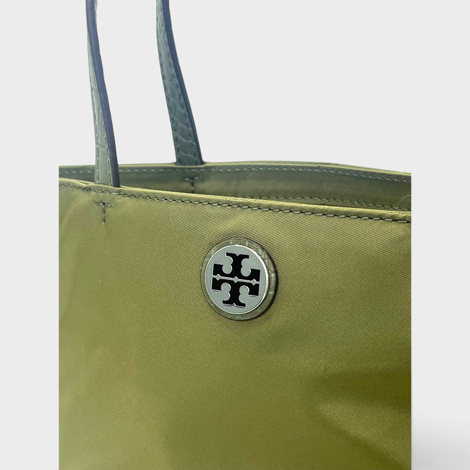 Supplied Fashion green khaki nylon mini tote bag featuring a silver Tory Burch logo emblem and structured handles.