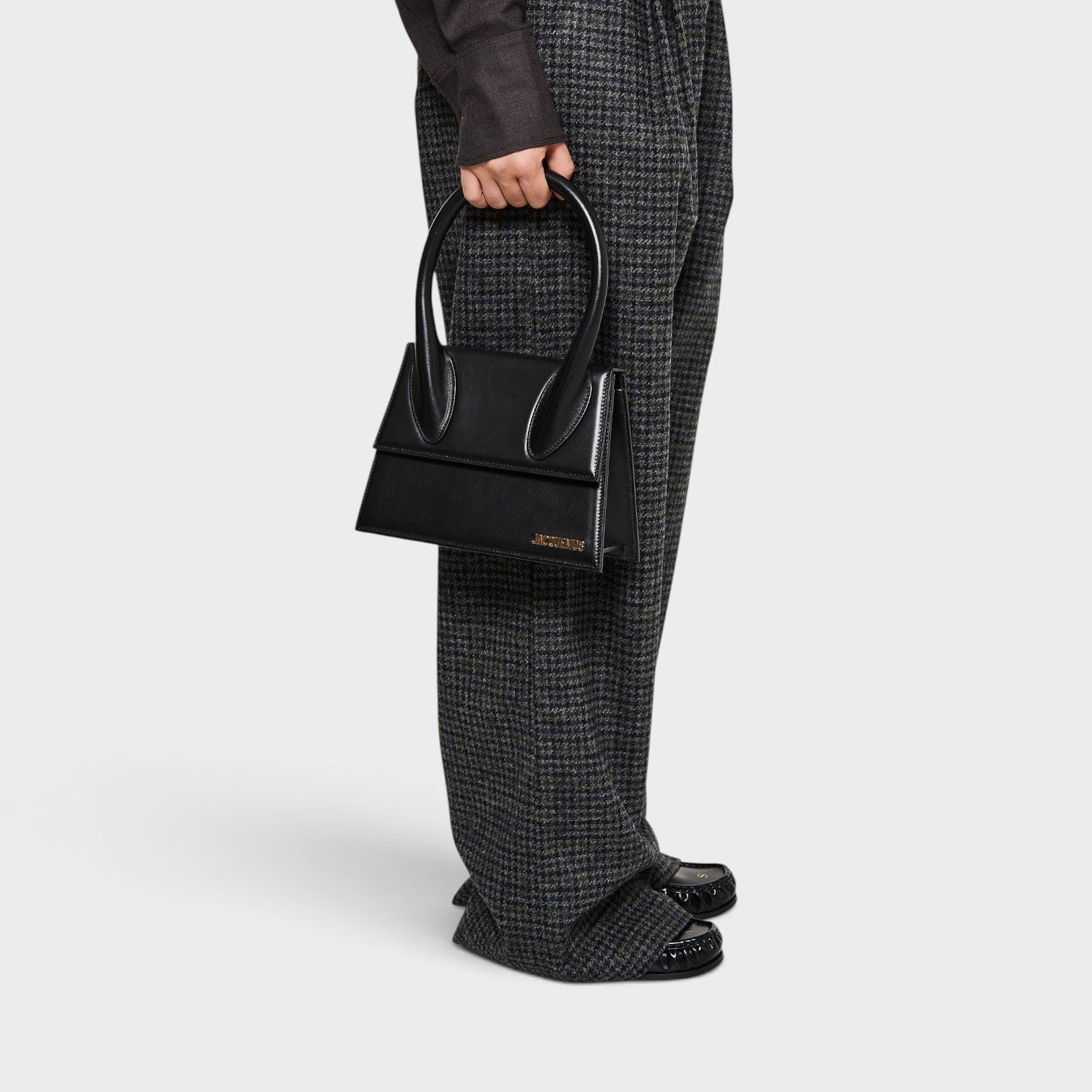 Supplied Fashion Jacquemus Le Grand Chiquito black structured handbag with silver hardware held by a model