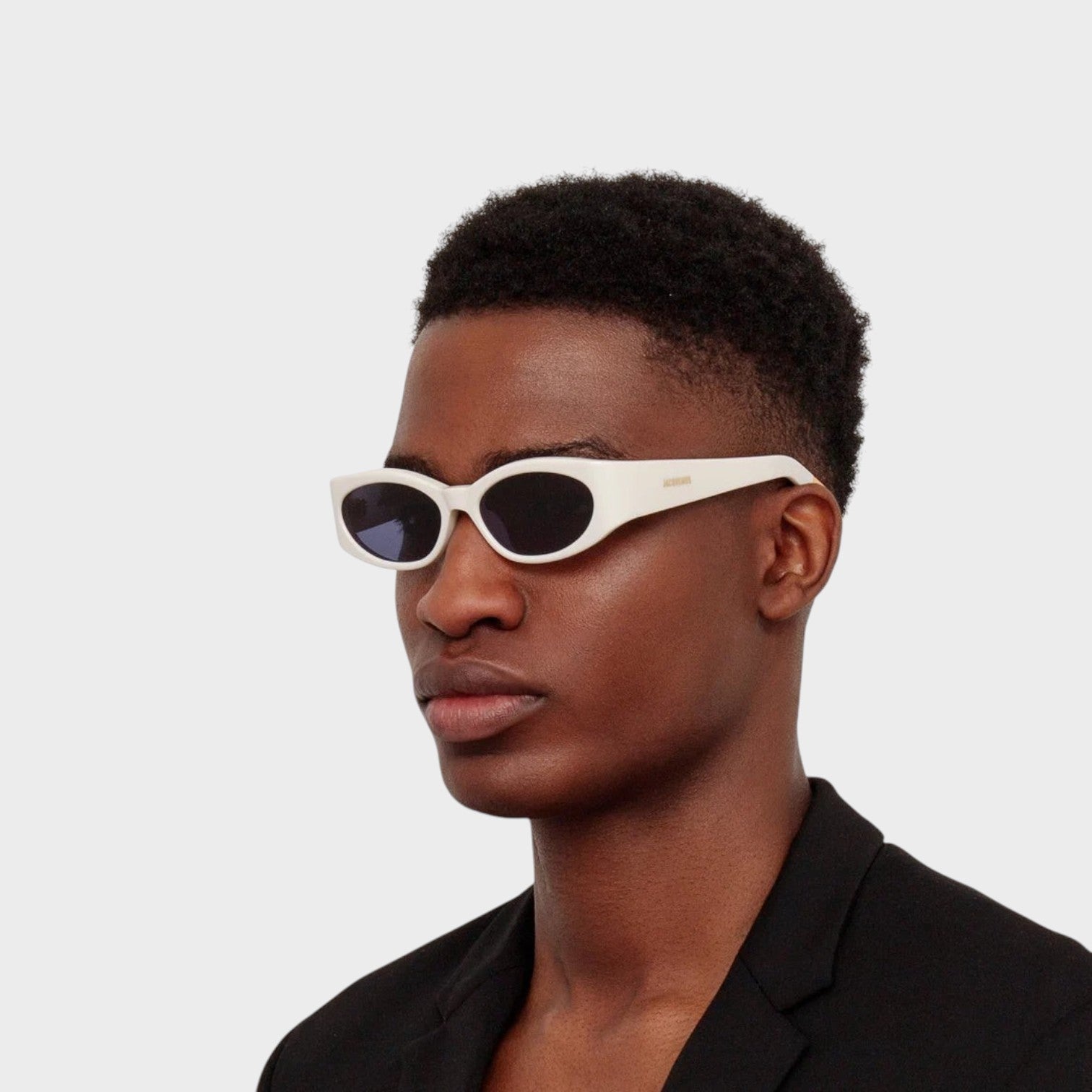 Supplied Fashion Jacquemus x Linda Farrow white oval sunglasses worn by a man in a black blazer