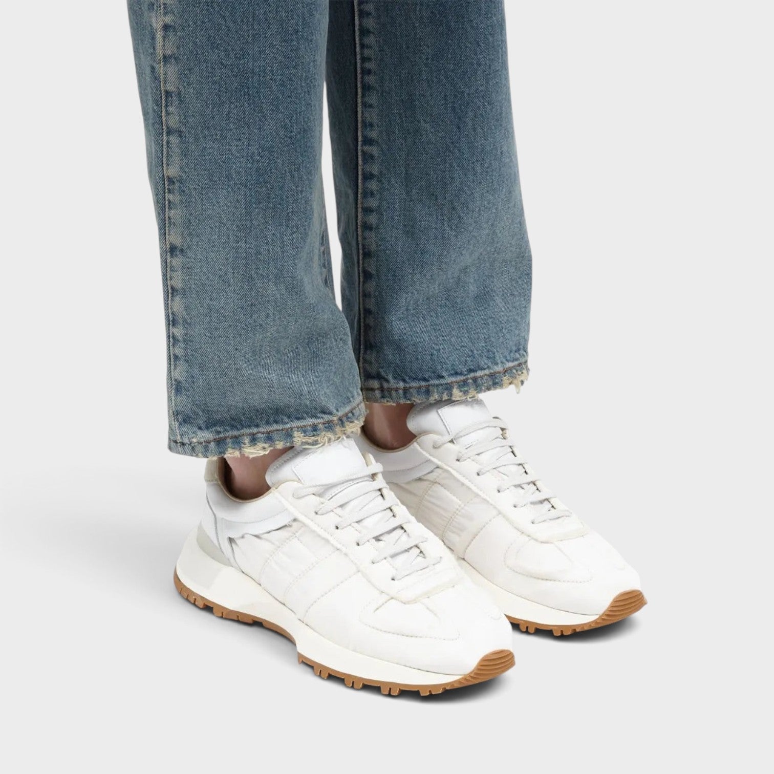 Supplied Fashion Maison Margiela 50-50 white leather sneakers with split-sole design worn with blue denim jeans.