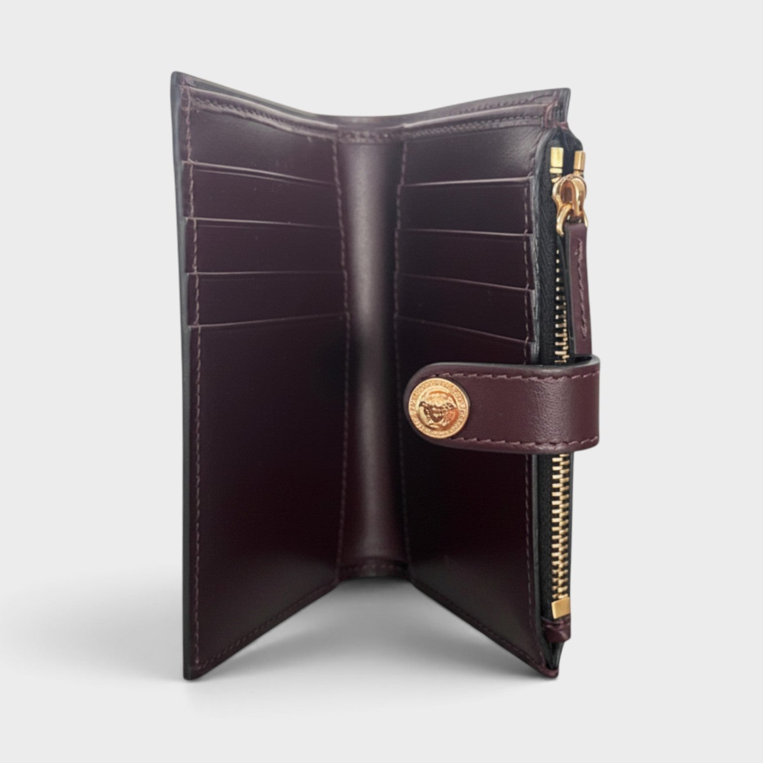 Supplied Fashion maroon brown calf leather compact wallet with gold Medusa logo snap button and interior card slots.