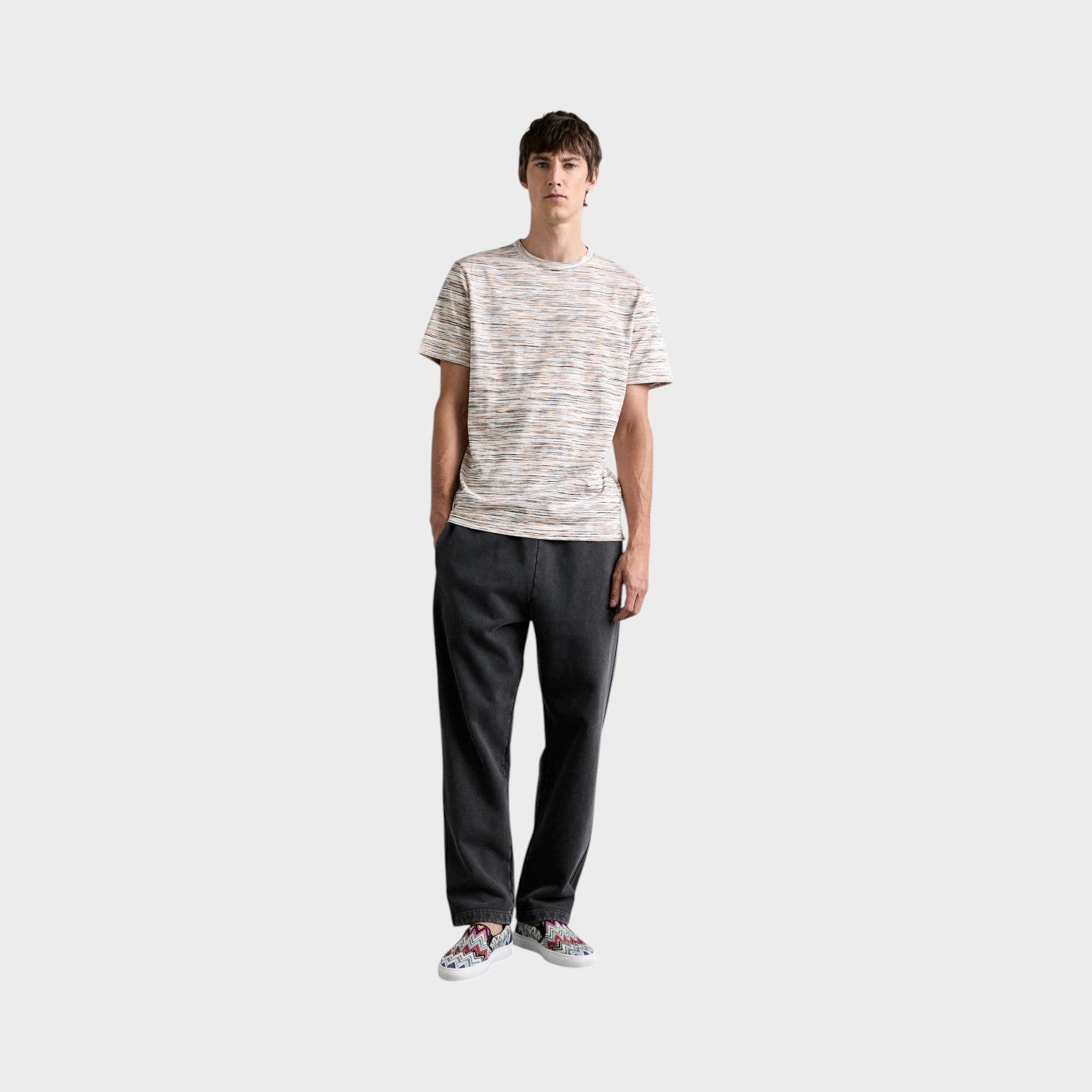 Supplied Fashion model wearing a Missoni space-dyed multi-coloured cotton short-sleeve t-shirt with dark trousers.
