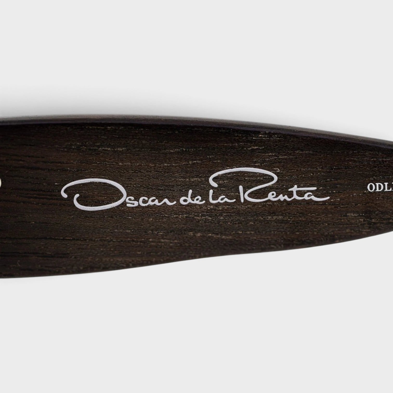 Supplied Fashion Linda Farrow oversized sunglasses temple detail featuring the Oscar de la Renta logo on dark wood grain