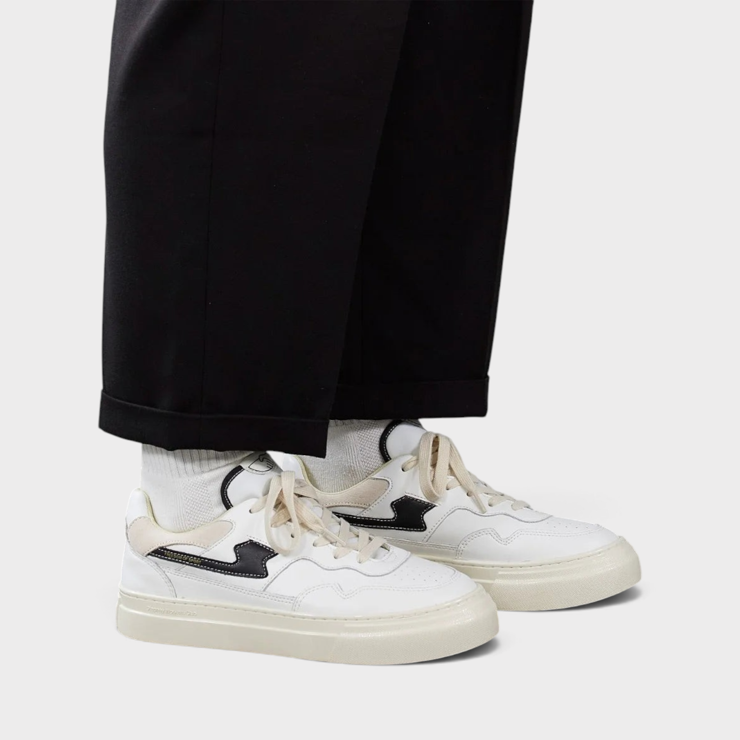 Supplied Fashion Pearl S-Strike white and black leather sneakers worn with white socks and black trousers