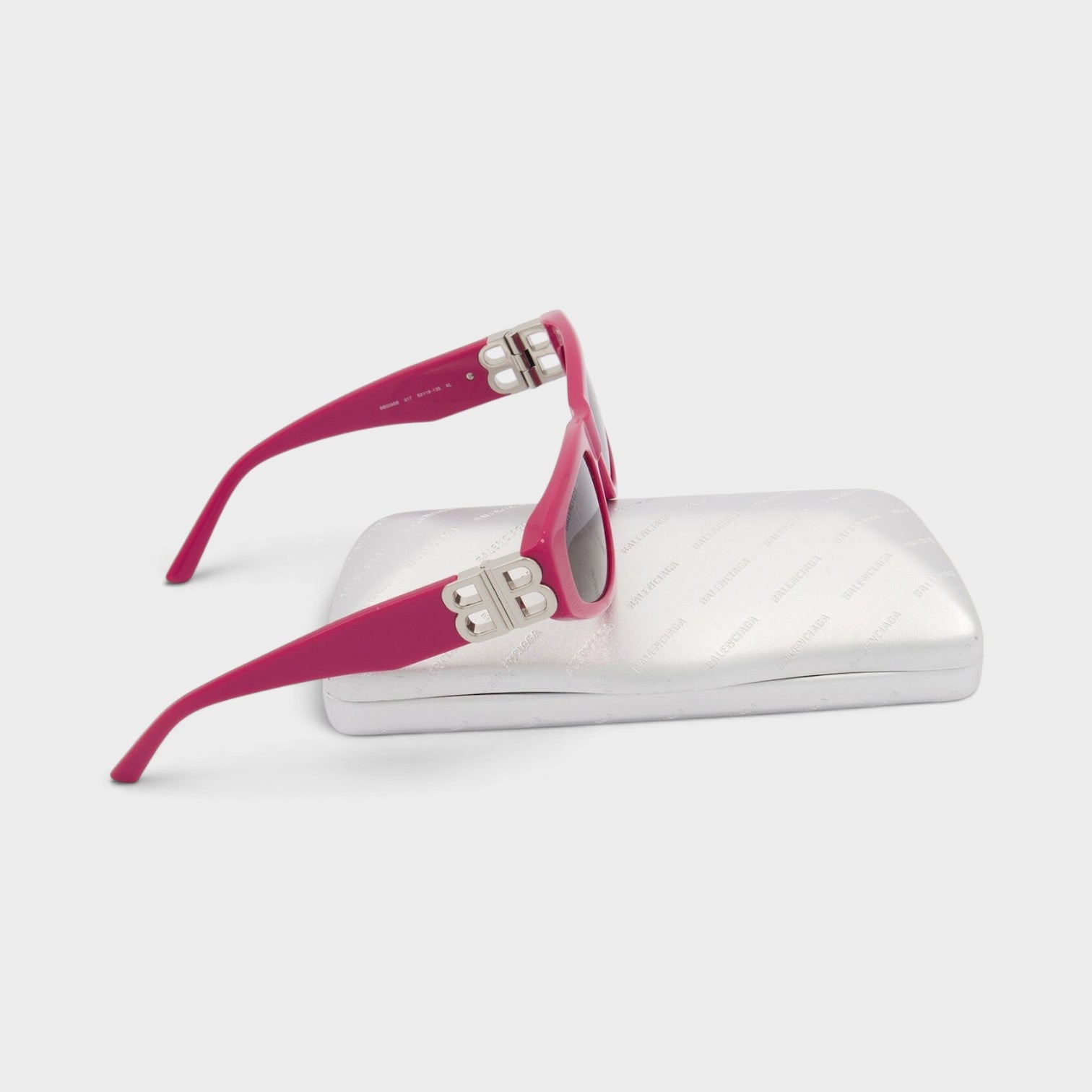 Supplied Fashion pink cat eye sunglasses with silver logo plaque on the temple, resting on a metallic silver case.
