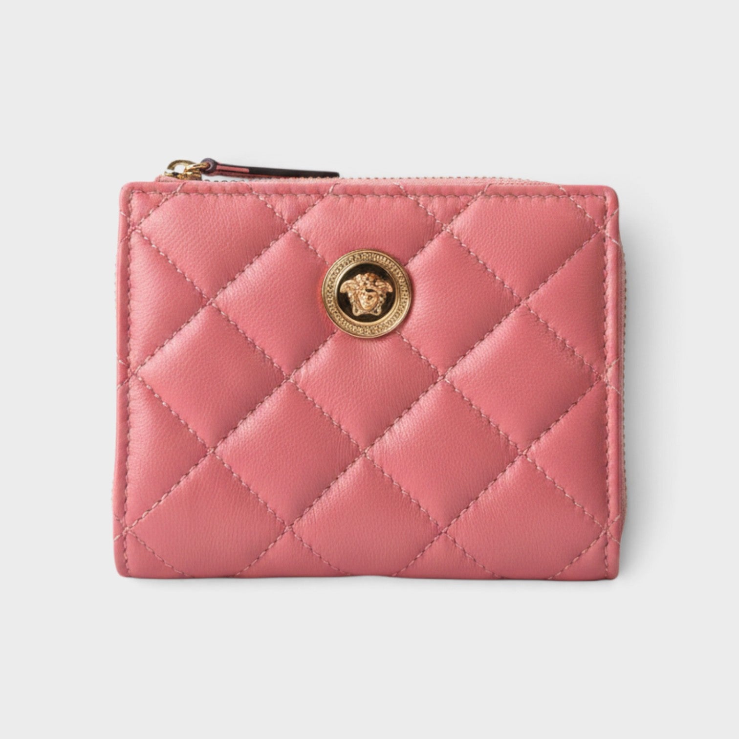 Supplied Fashion pink quilted leather wallet featuring a gold Medusa head emblem and zip closure.