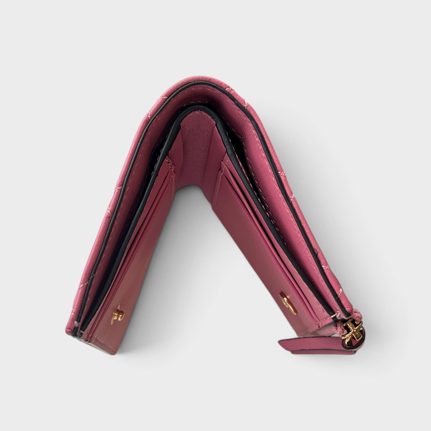 Supplied Fashion pink quilted wallet with Medusa head emblem and gold-tone hardware in a folded open view