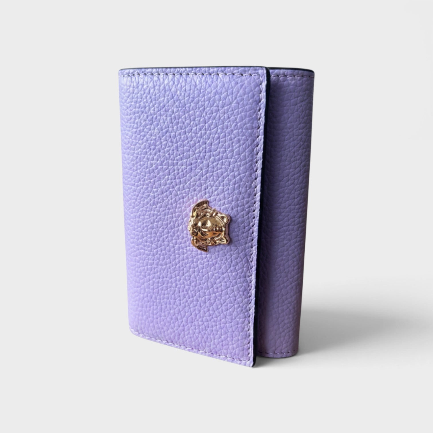 Supplied Fashion purple pebbled leather business card holder featuring a gold-tone Medusa head emblem.