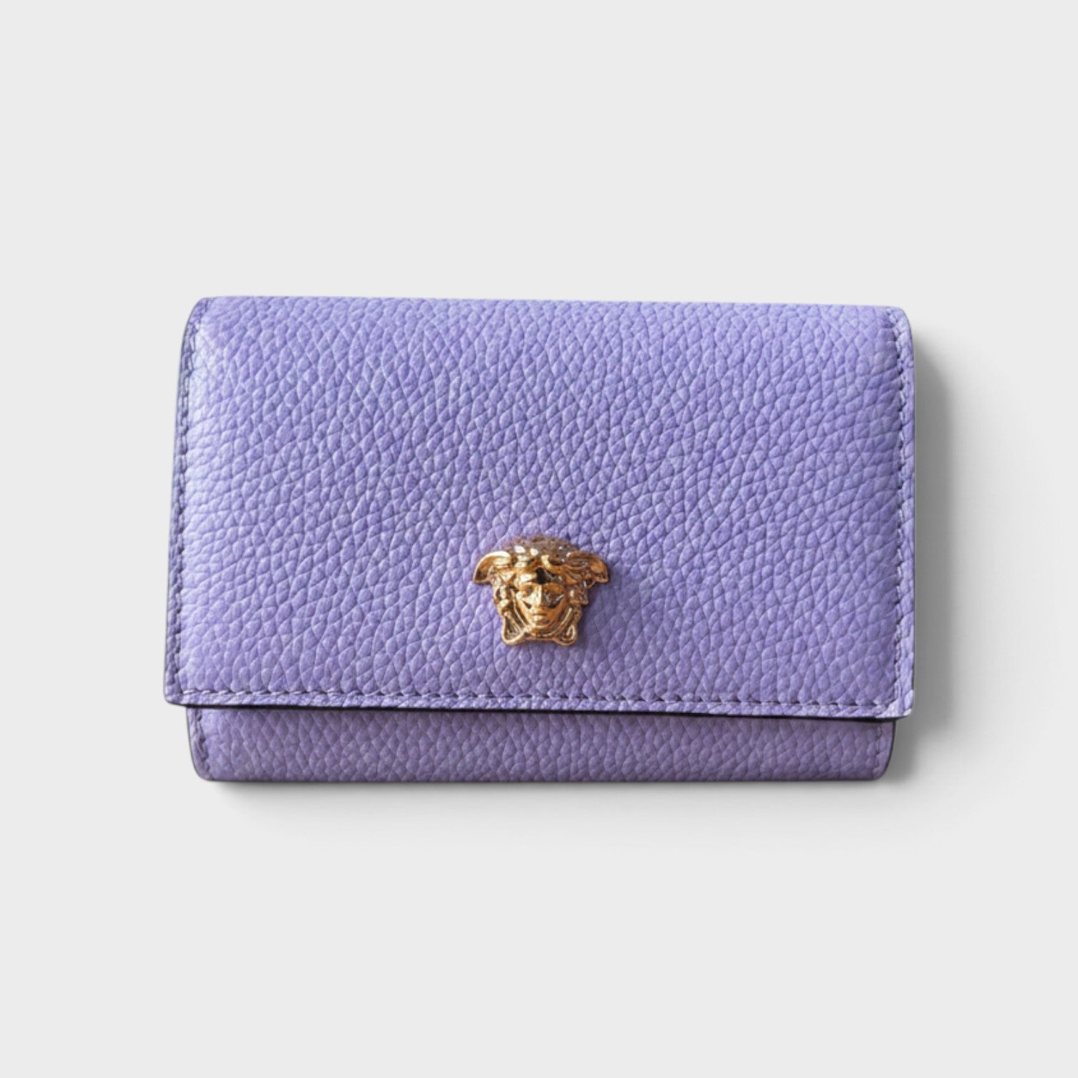 Supplied Fashion purple pebbled leather business card holder featuring a gold-tone Medusa head emblem.