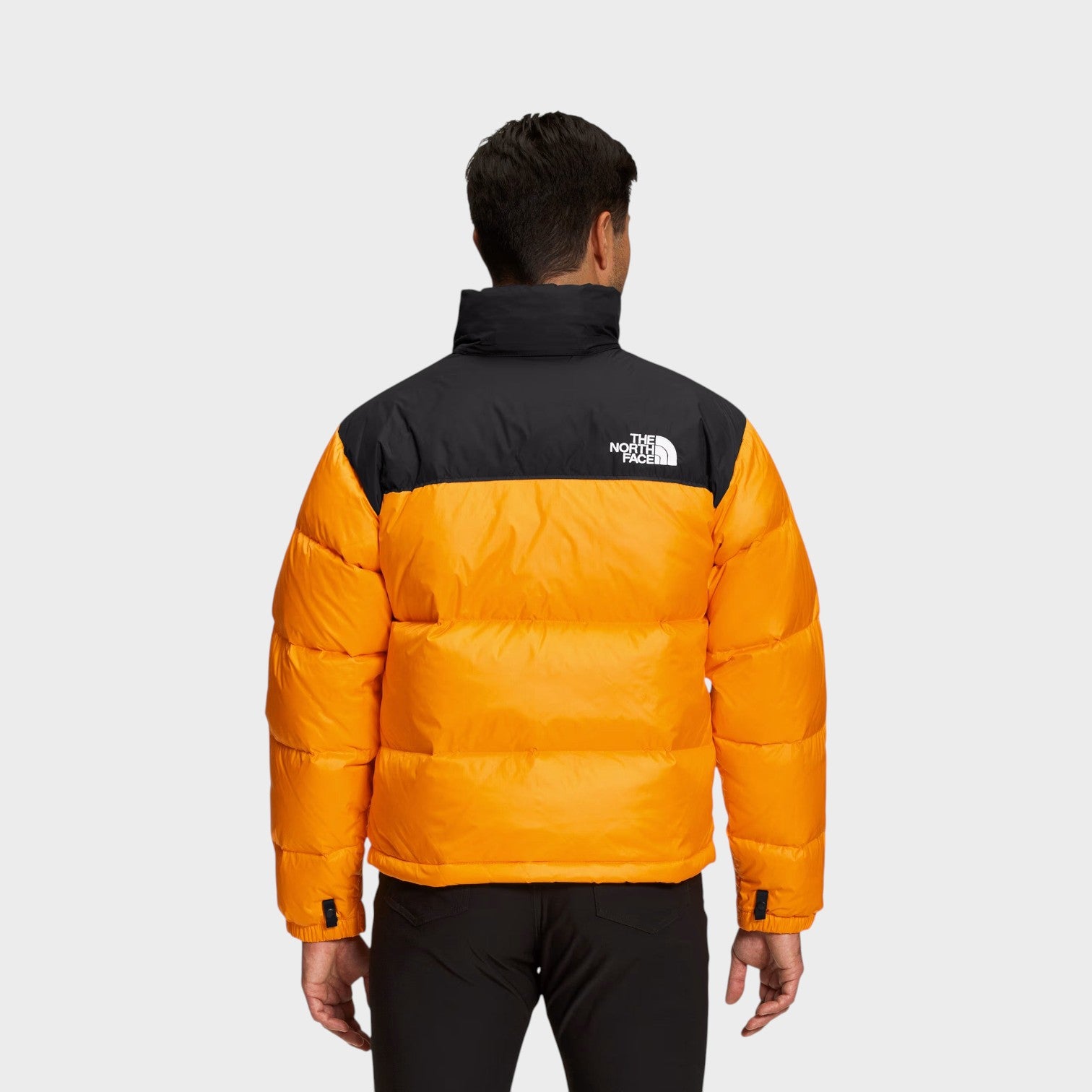 Back view of a man wearing a Supplied Fashion 1996 Retro Nuptse puffer jacket in vibrant Summit Gold yellow and black.