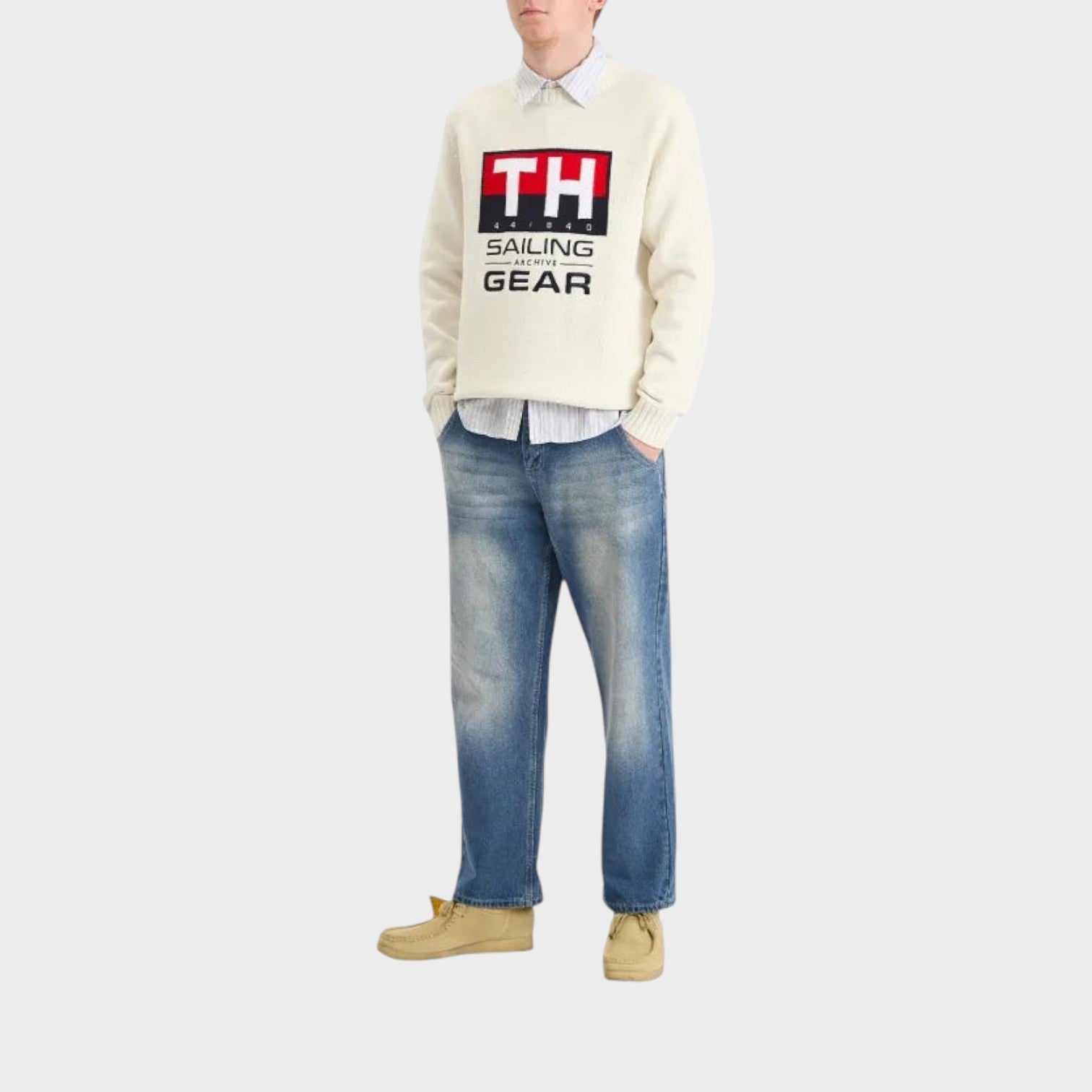 Supplied Fashion white crewneck knit sweater with nautical logo graphic worn with blue jeans and tan shoes